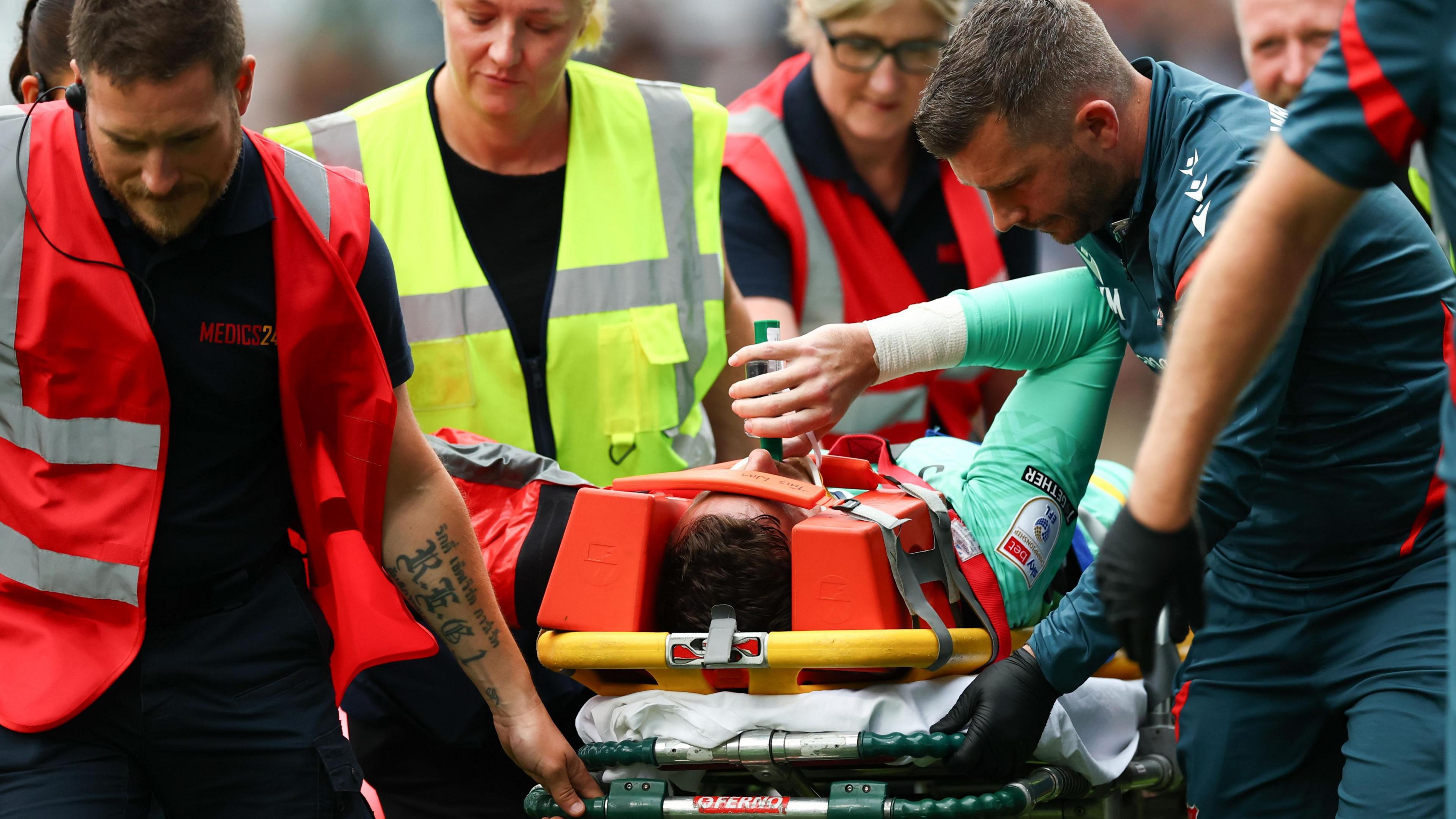 Wrexham goalkeeper Danny Ward is carried off injured at Millwall