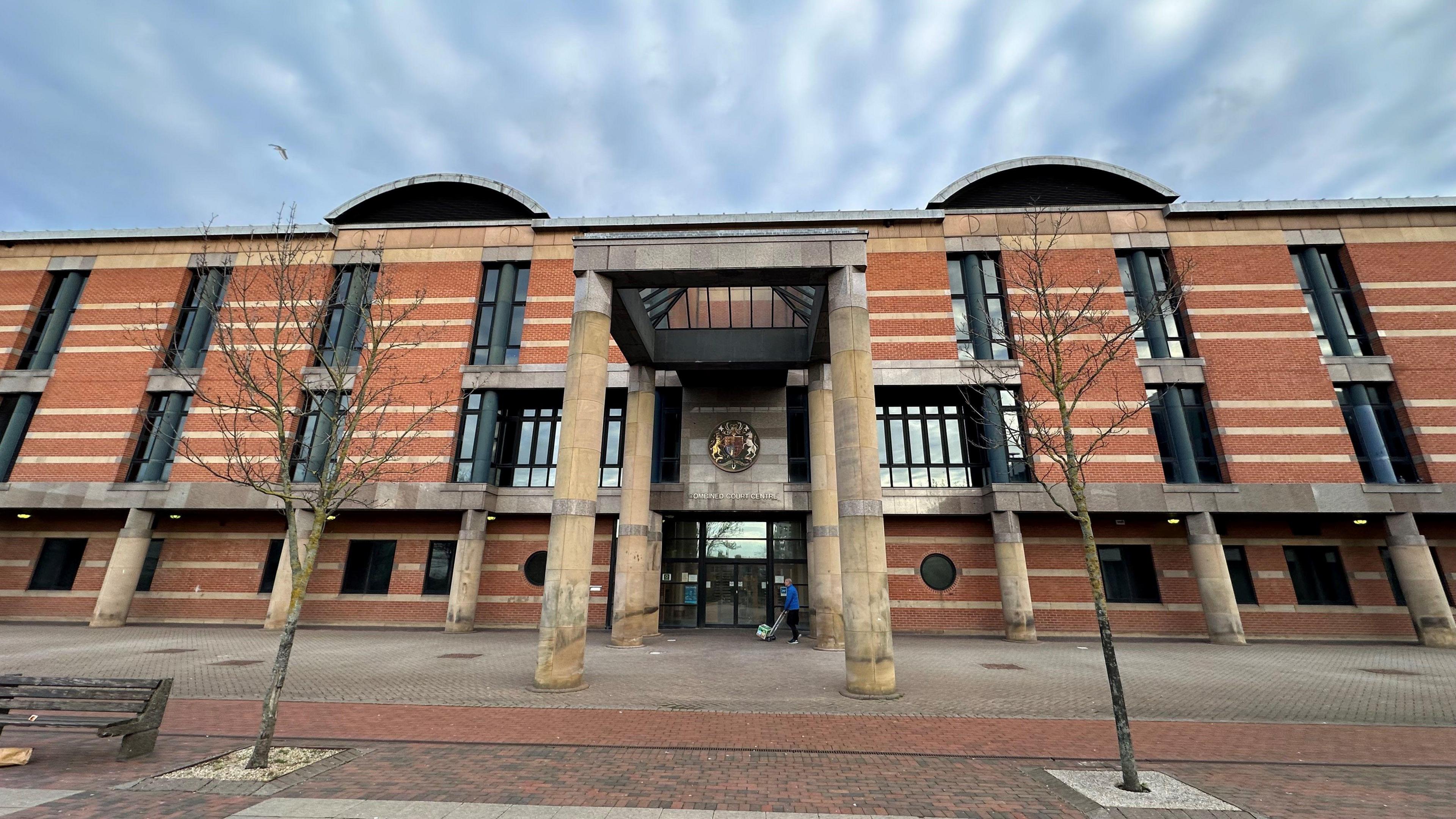 A red brick court building with four large stone pillars around the front door.