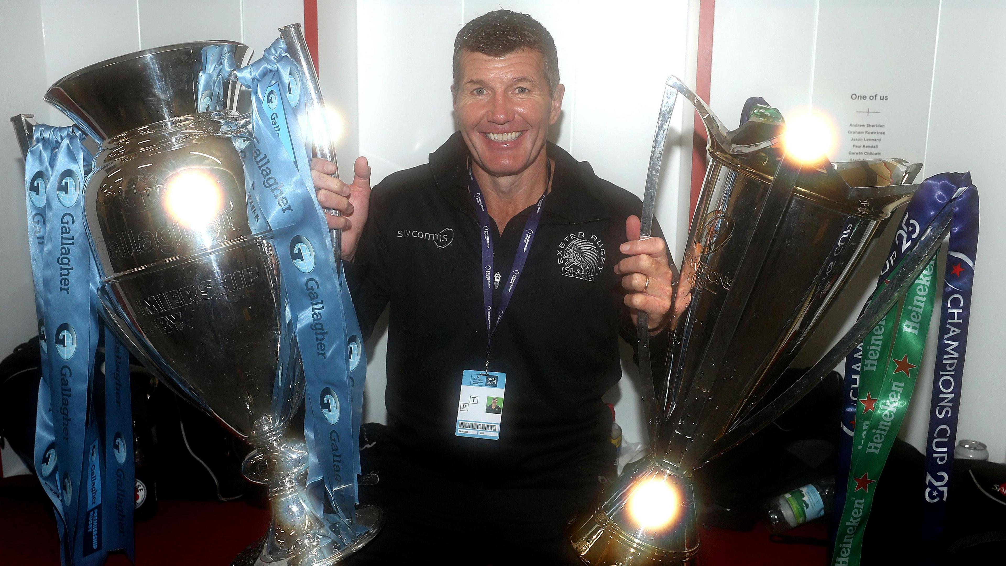 Rob Baxter holds the Premiership and Champions Cup trophies