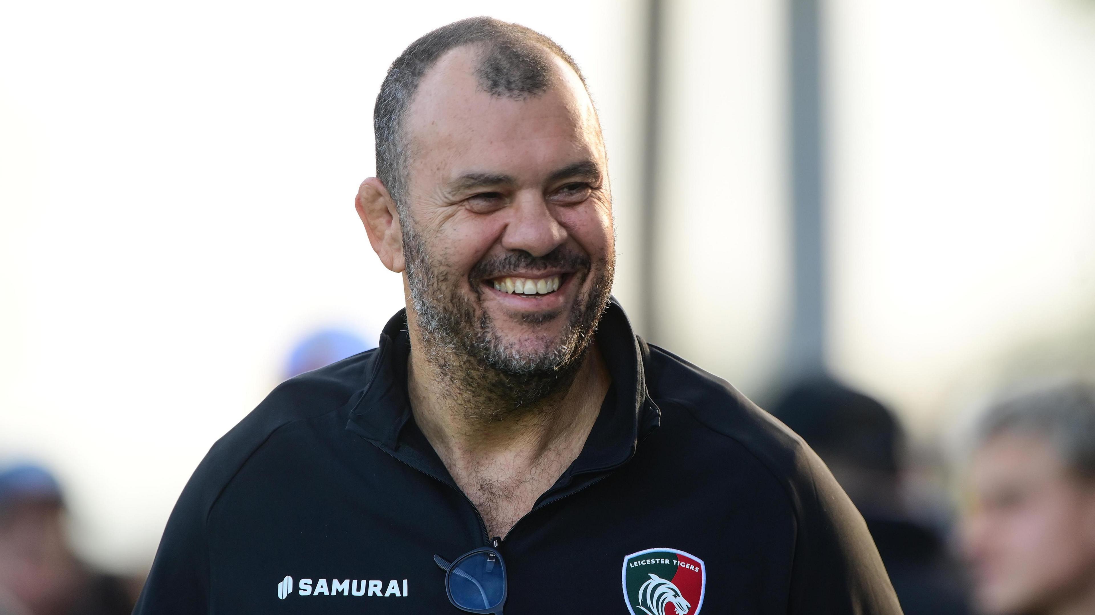 Michael Cheika smiles while walking past Leicester Tigers fans