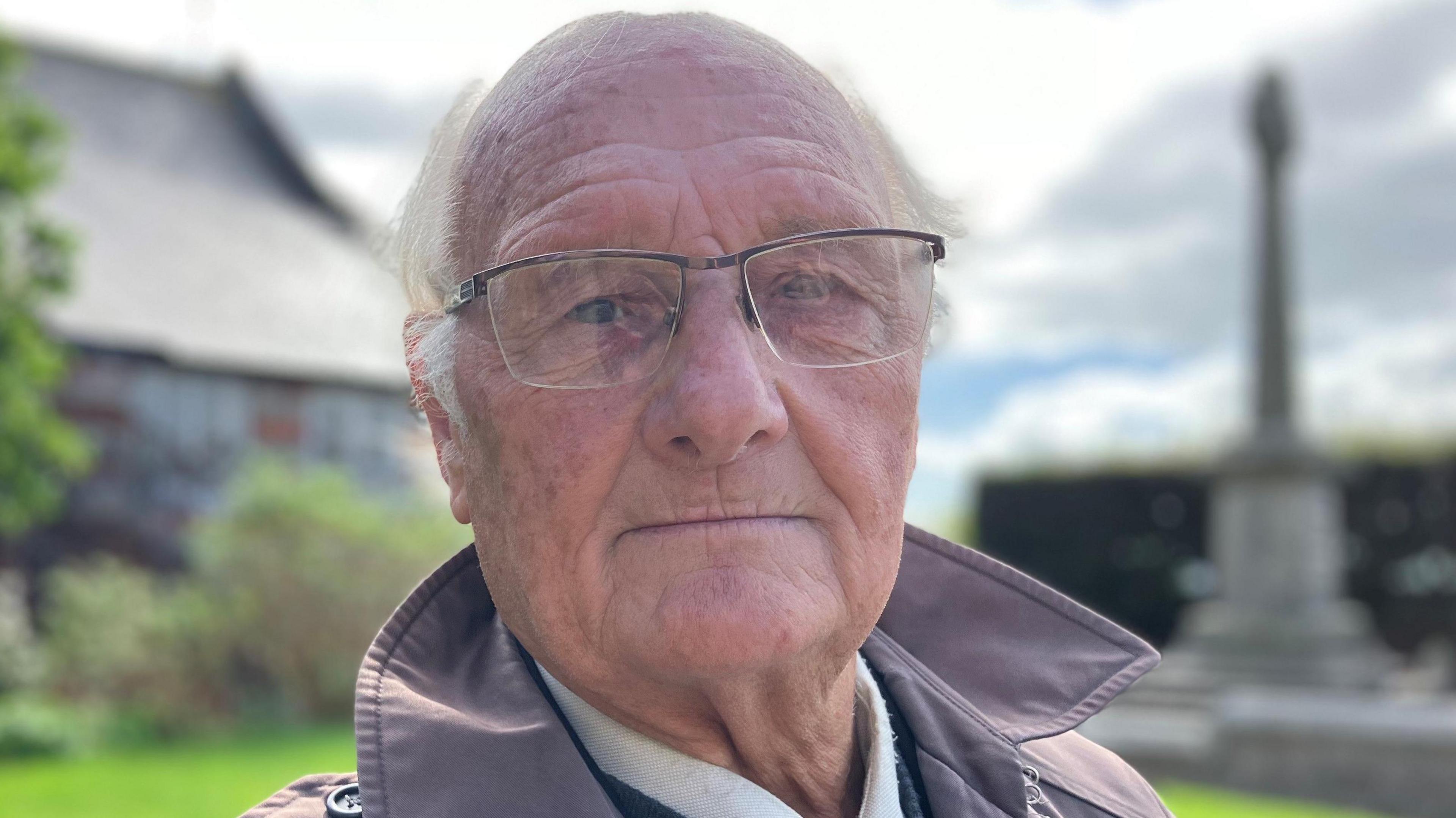 Man wearing glasses in front of World War One memorial 