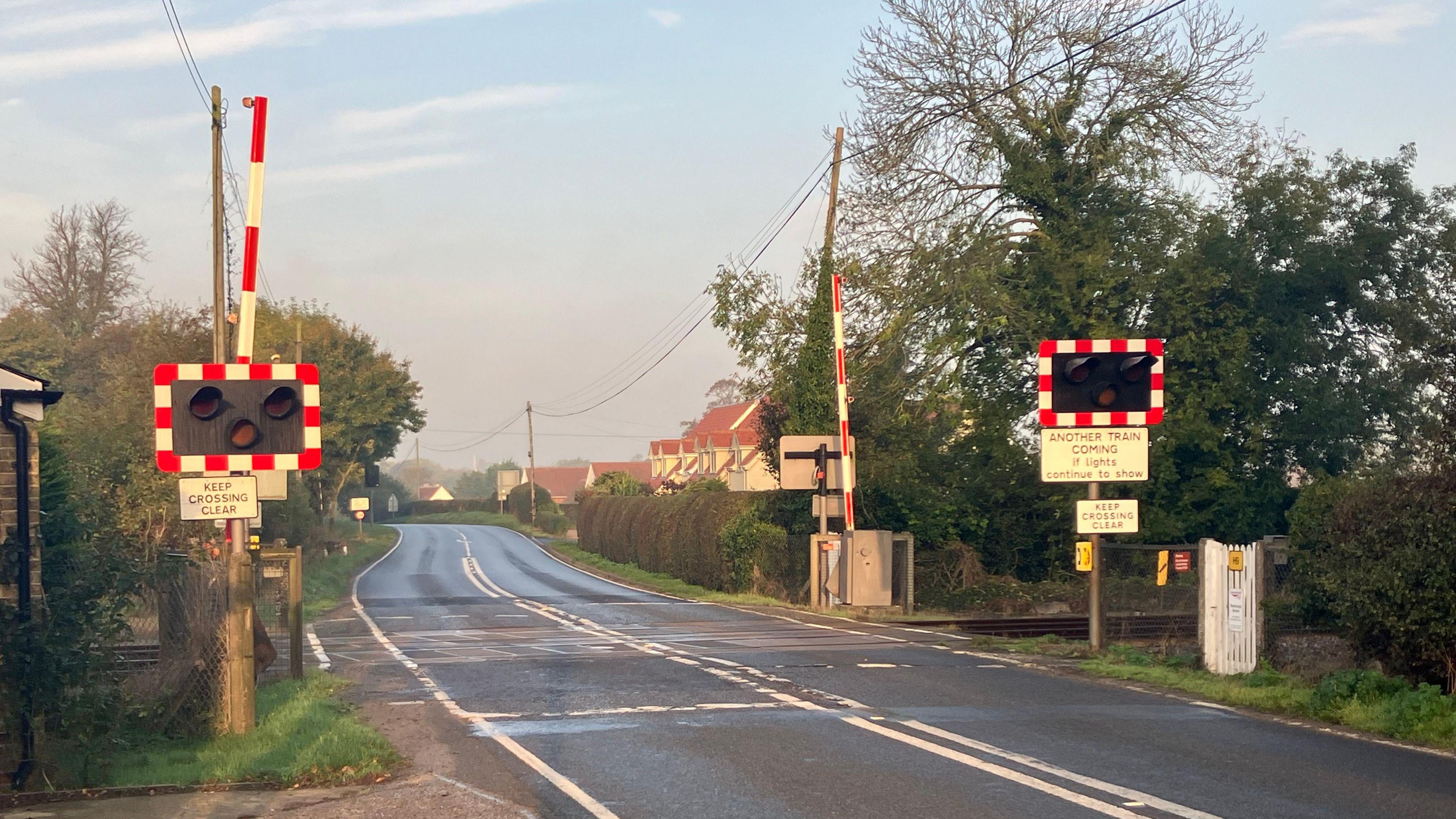 A level crossing. There are tracks running across the road and warning signs.