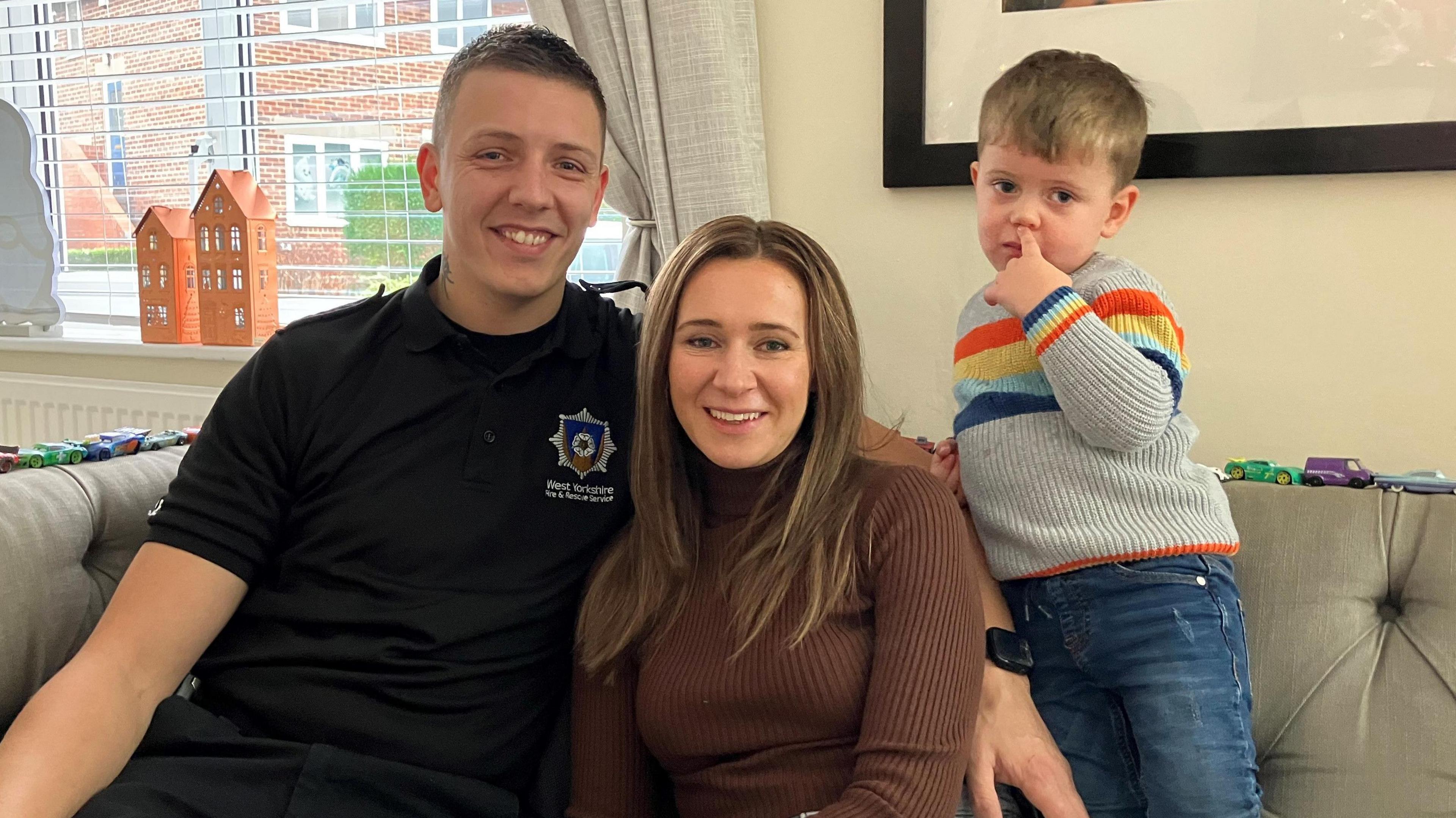 A young couple on a sofa with their two-year-old son