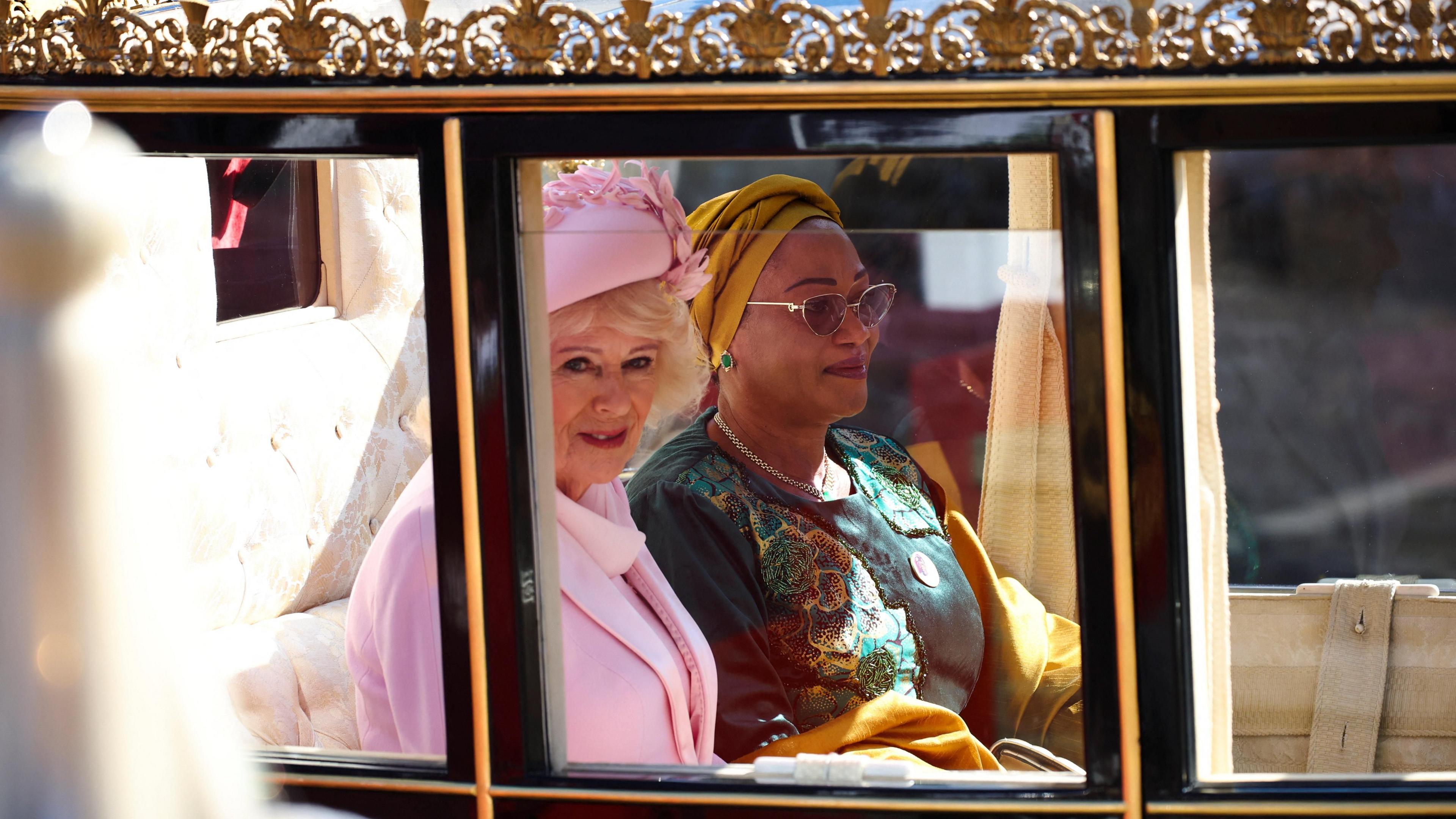 Mbretëresha Camilla dhe Zonja e Parë e Nigerisë, Oluremi Tinubu, shikojnë nga një karrocë.