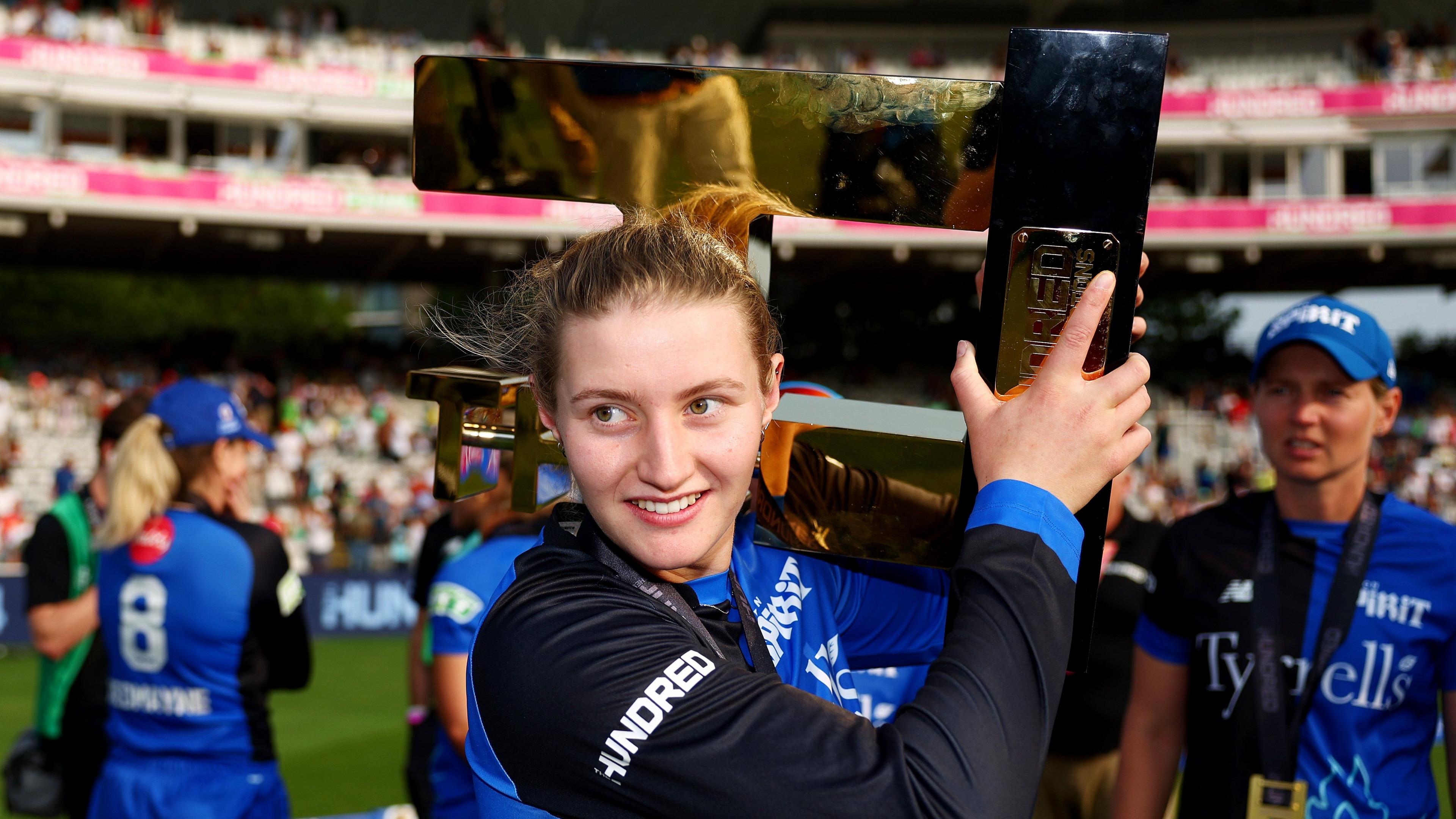 London Spirit spinner Charlie Dean holds The Hundred 2024 trophy over her shoulder