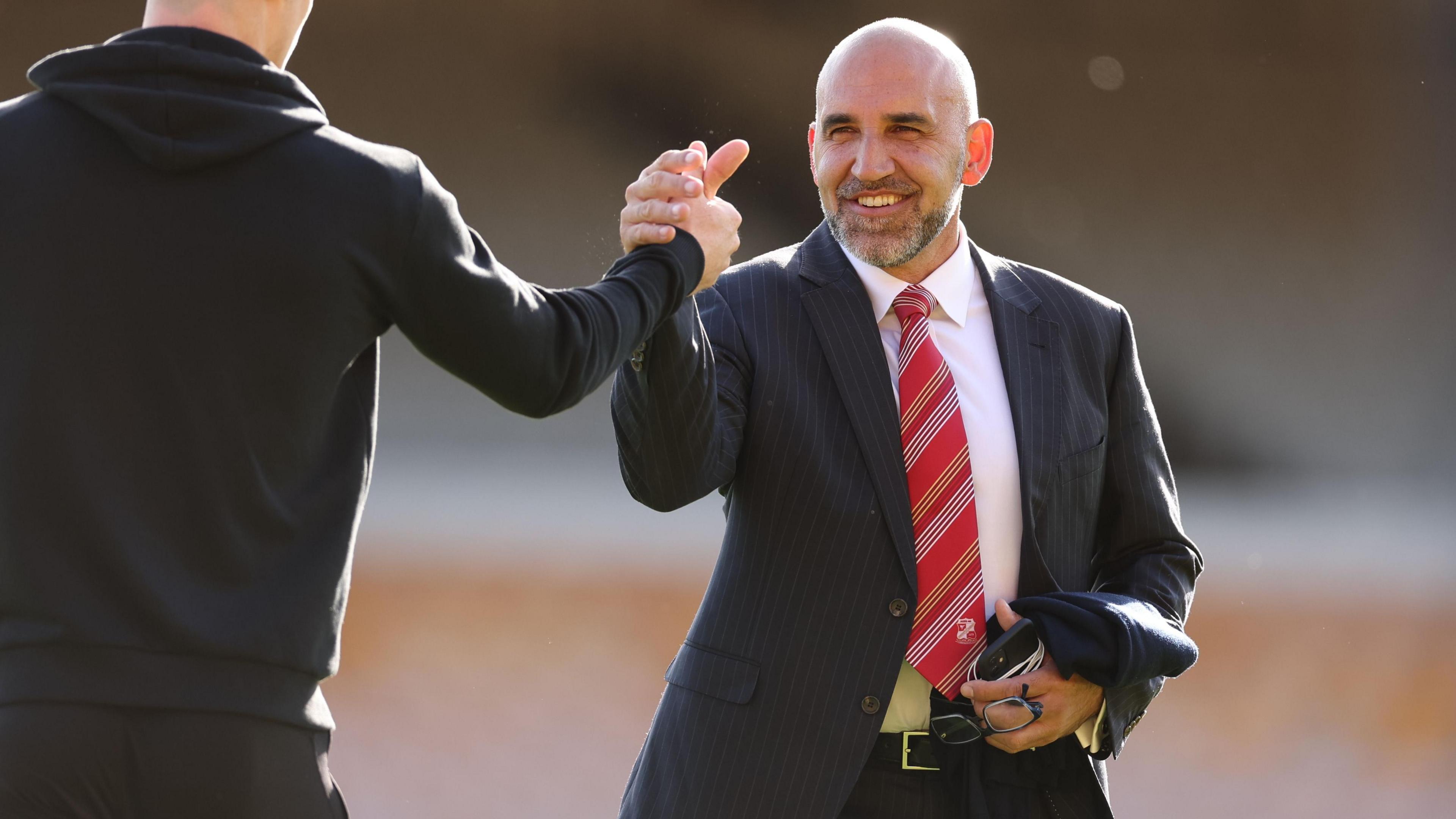 Clem Morfuni shakes someone's hand while standing on the pitch at the County Ground