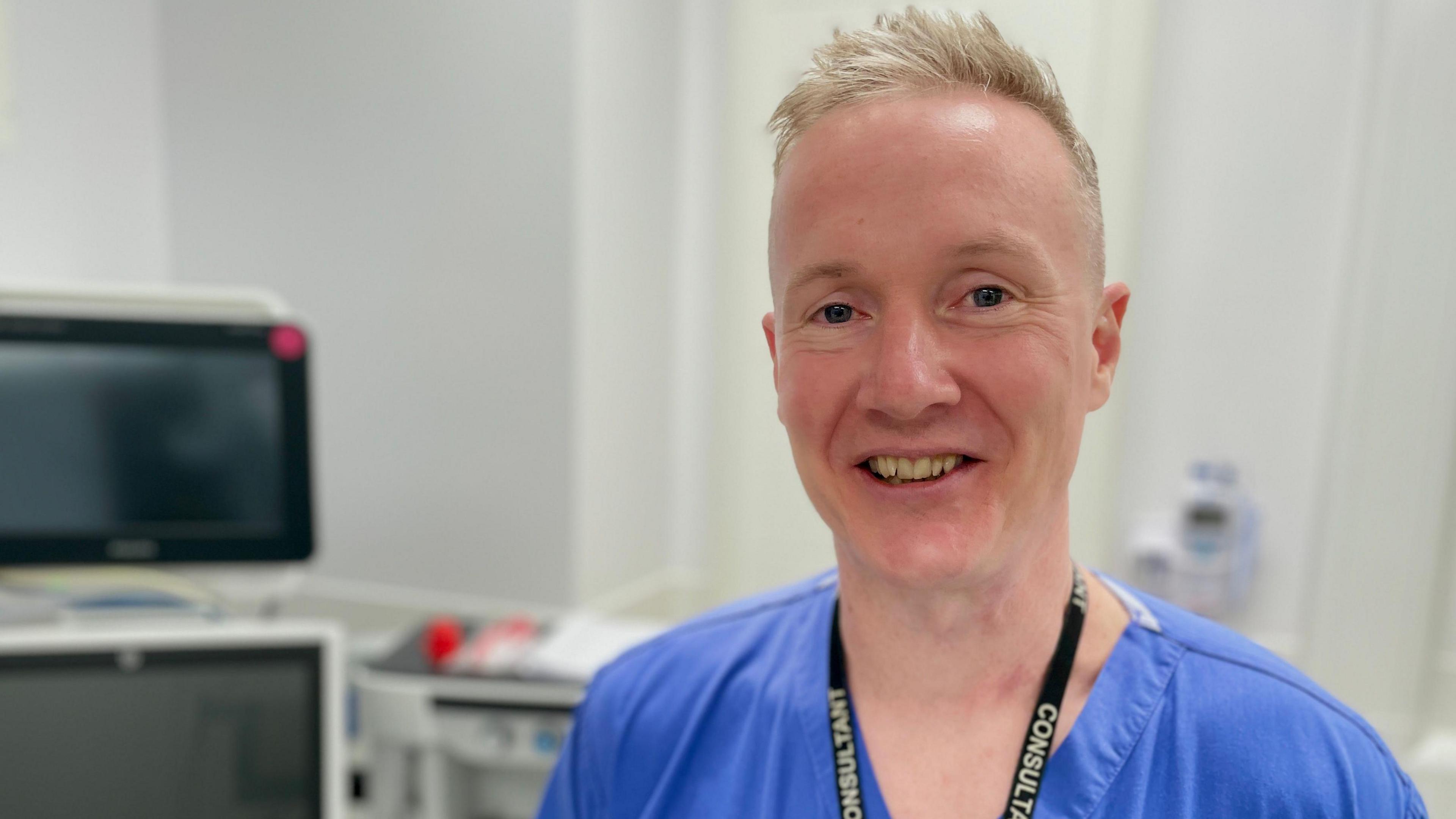 A doctor in blue surgical scrubs in a hospital room