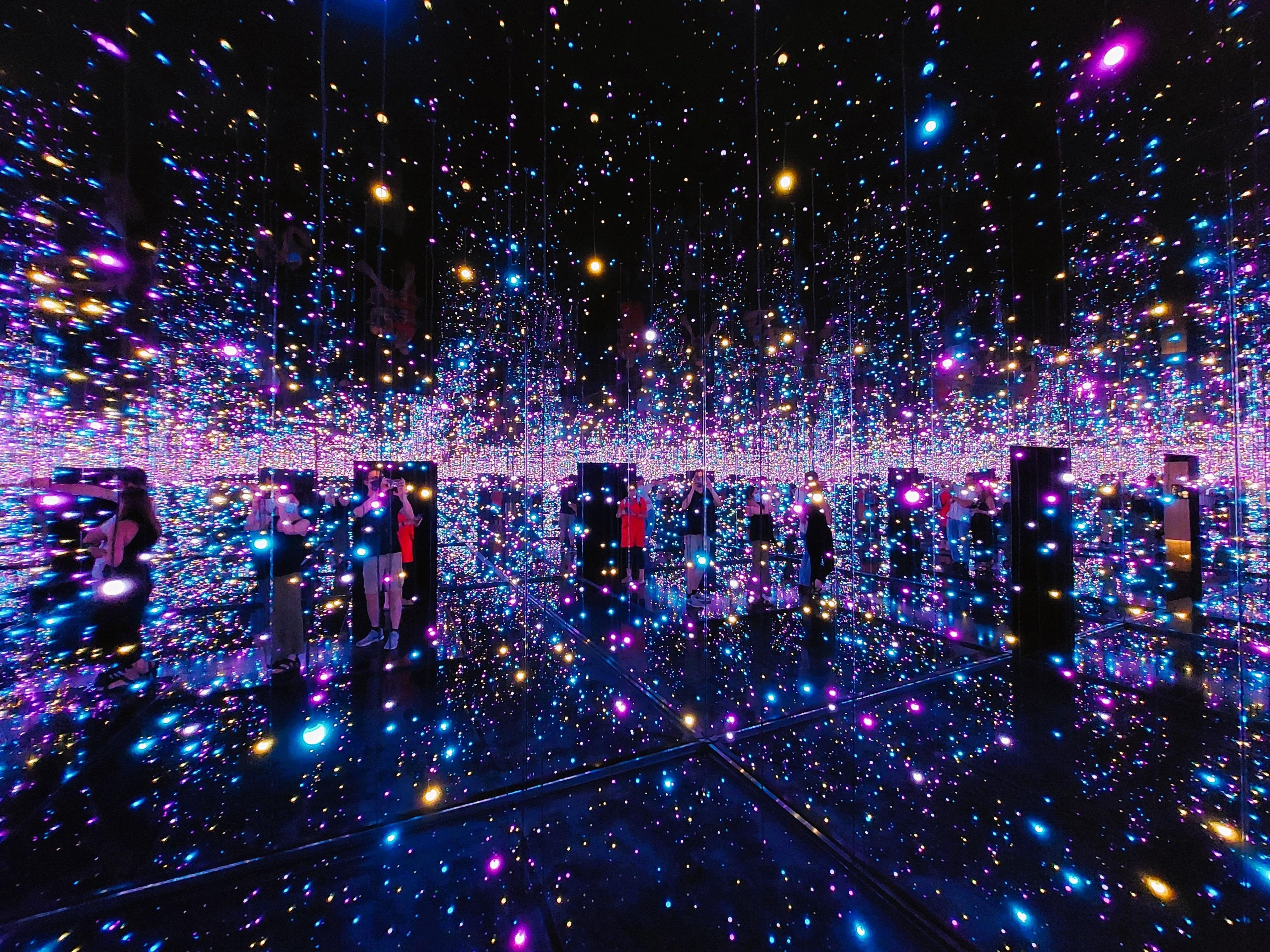 Bright lights in an infinity room. The room is dark and the speckled lights are shades of purple and blue.