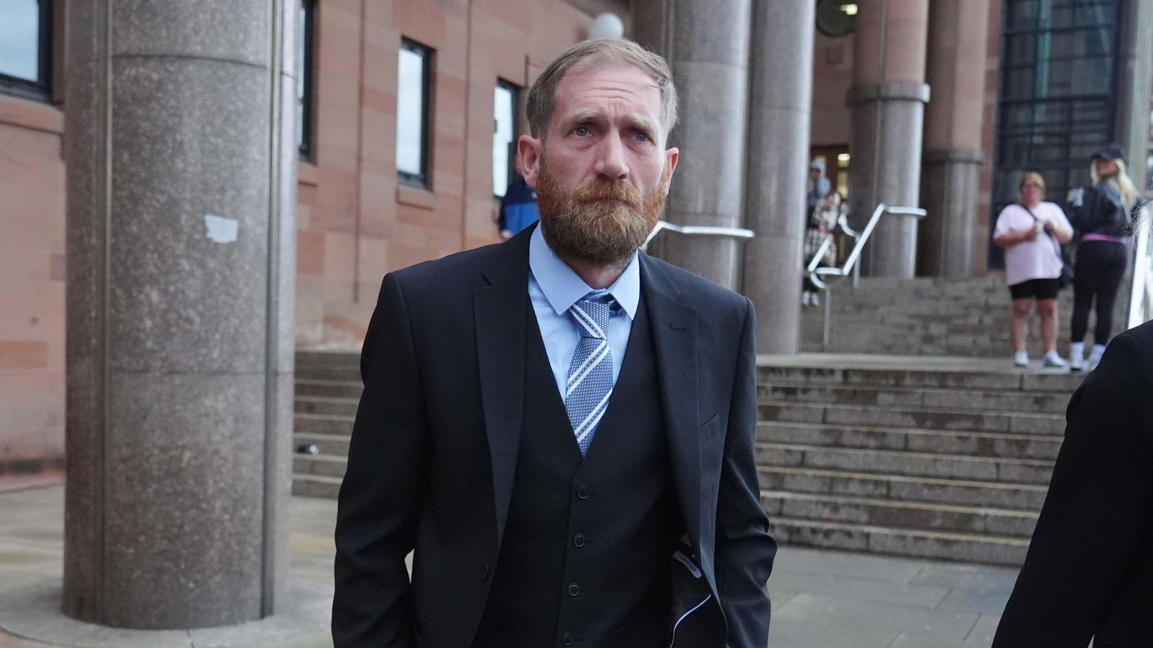 Bearded Daniel Graham, wearing a suit and tie, leaves Newcastle Crown Court.