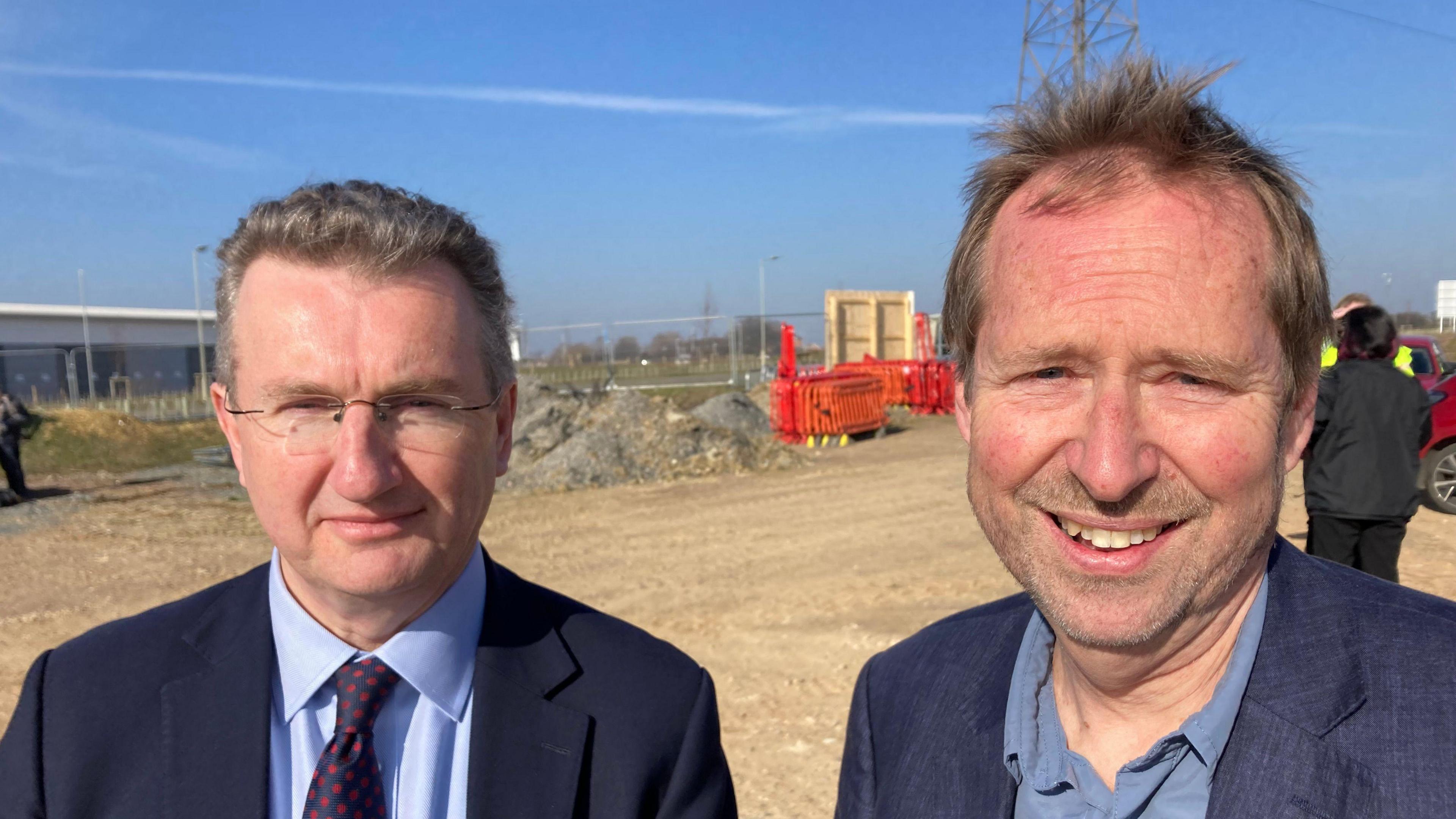 Steve Beel stands next to Richard Winch on the site where the new innovation centre will be building. Mr Beel wears a navy suit with a light blue shirt underneath and a navy tie with red spots. Mr Winch wears a navy suit jacket with a blue shirt underneath. 