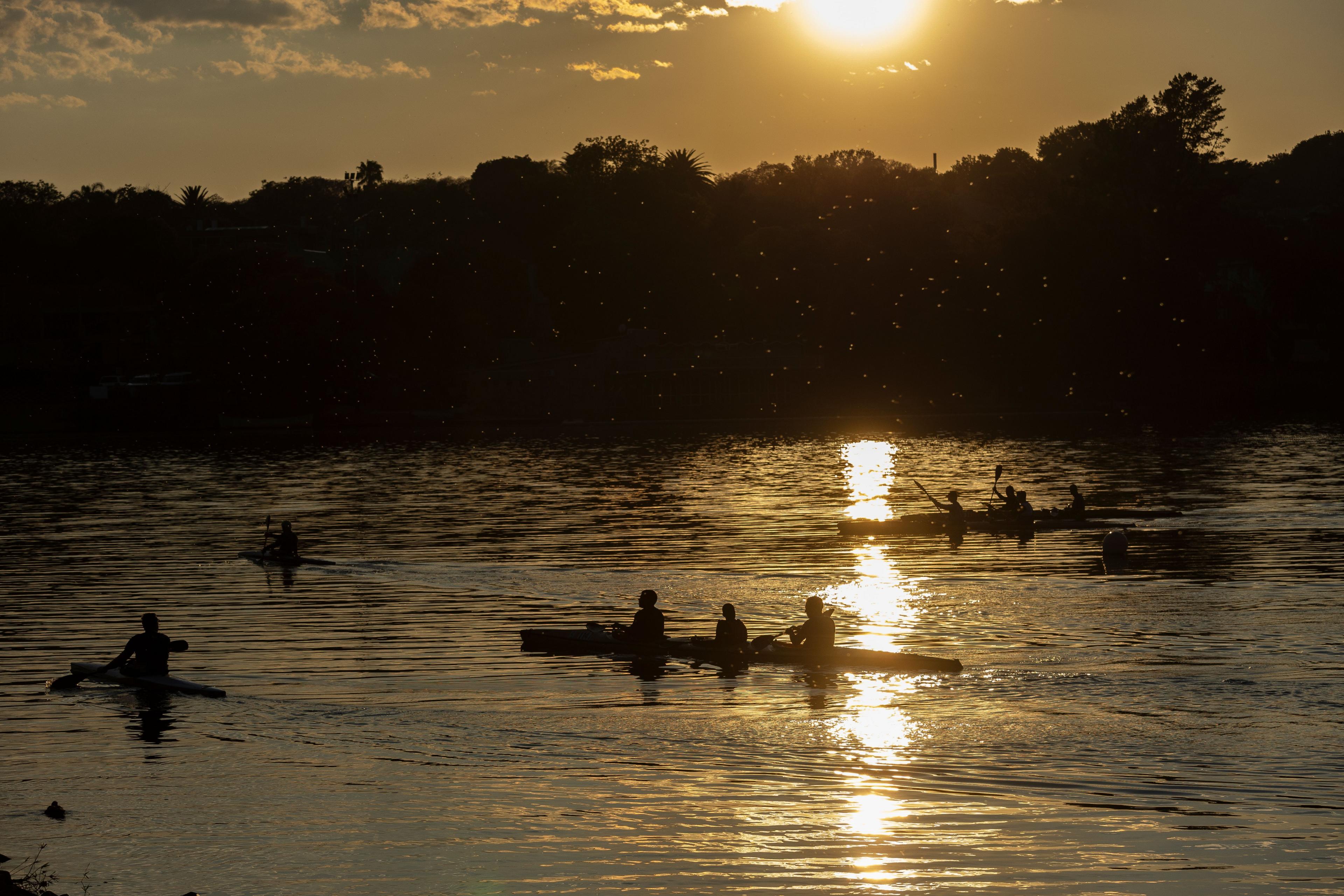 People in canoes paddle across water.