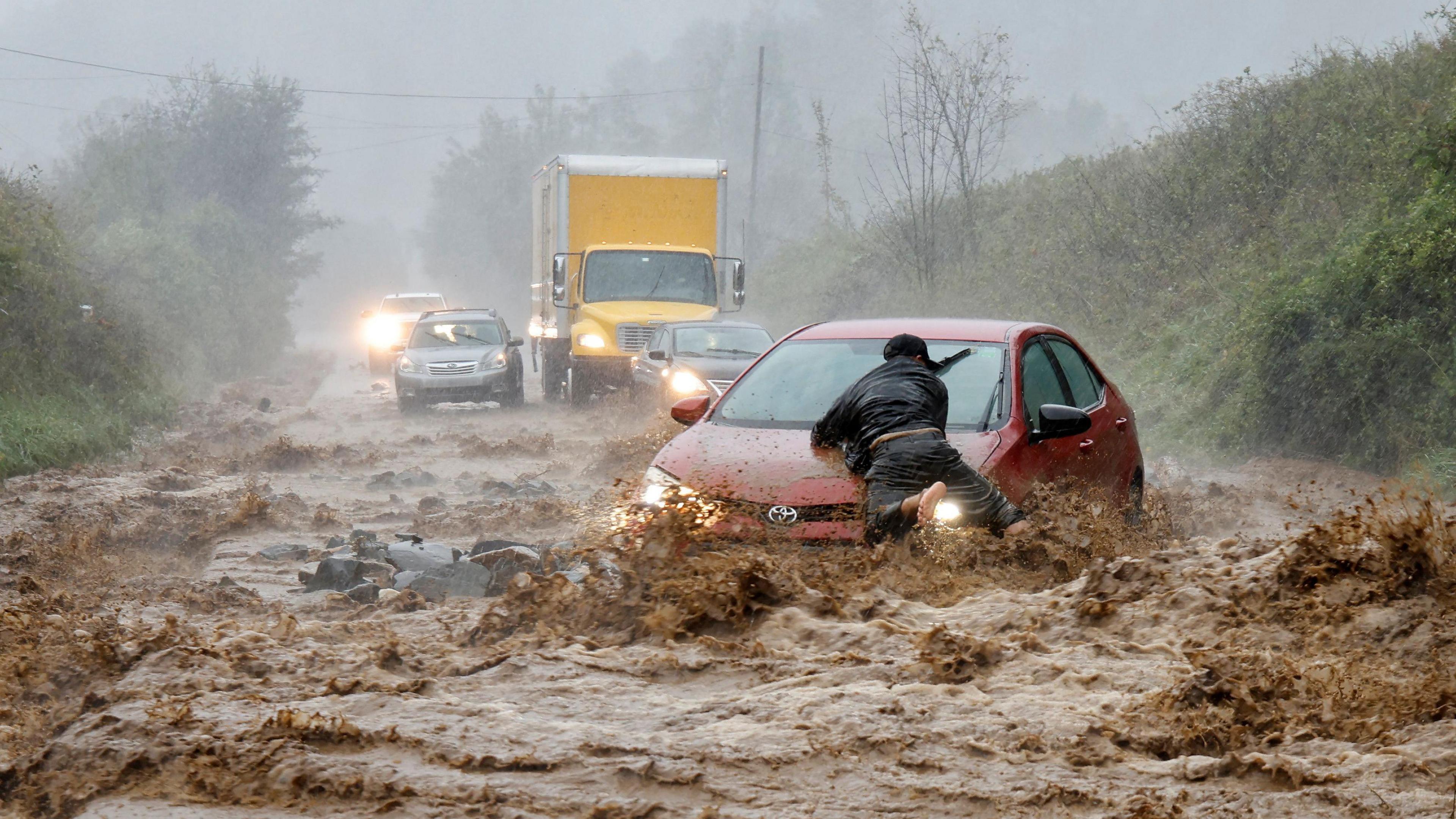 A man on top of a car in a flood in North Carolina