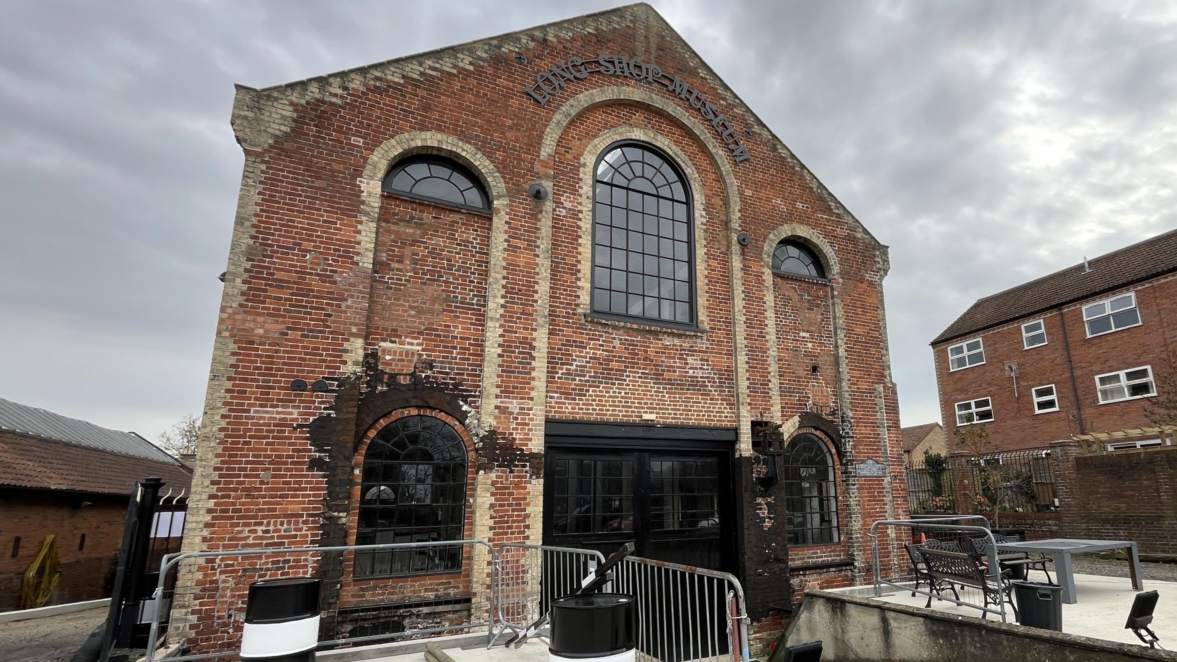 The exterior of the Long Shop Museum. It is a large red brick building with large windows across several floors. 