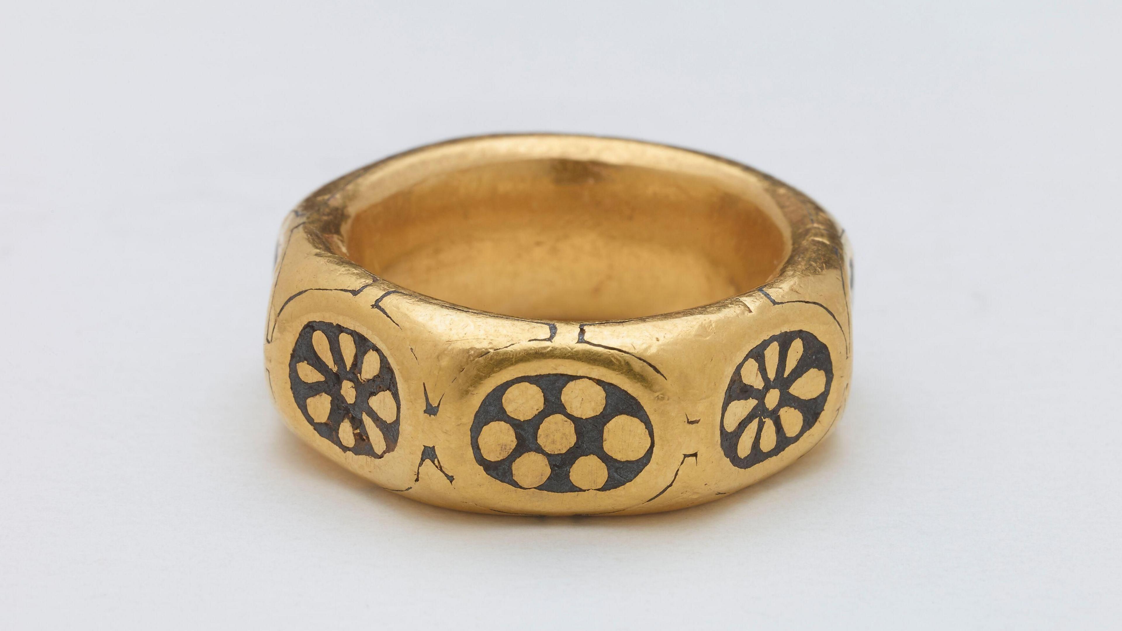 A large gold ring, with eight sides, each with a different floral design in lead. The ring dates from the ninth century and is part of the Herefordshire hoard which was found in a field in 2015.