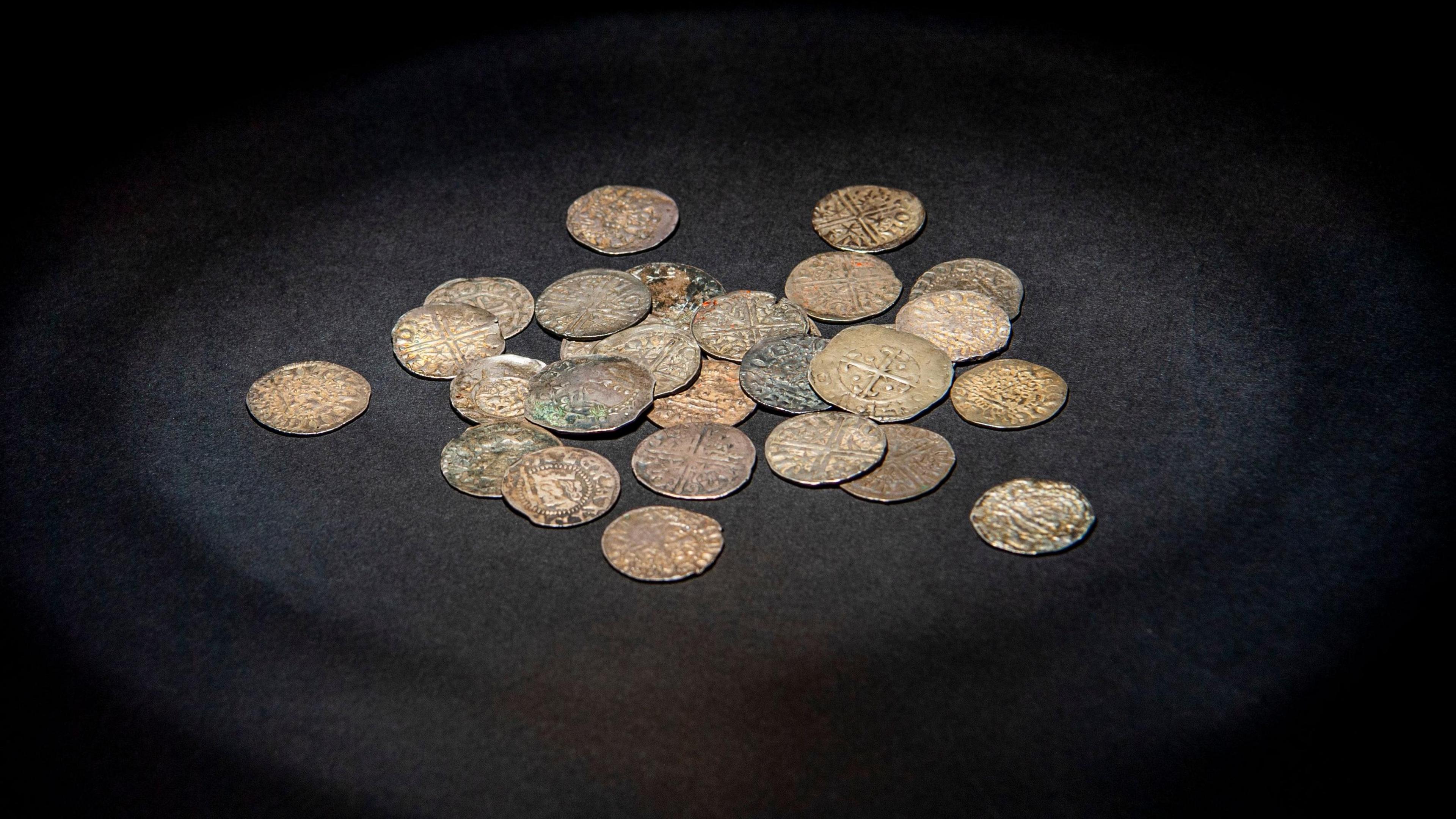 A collection of old coins lying around on a black surface