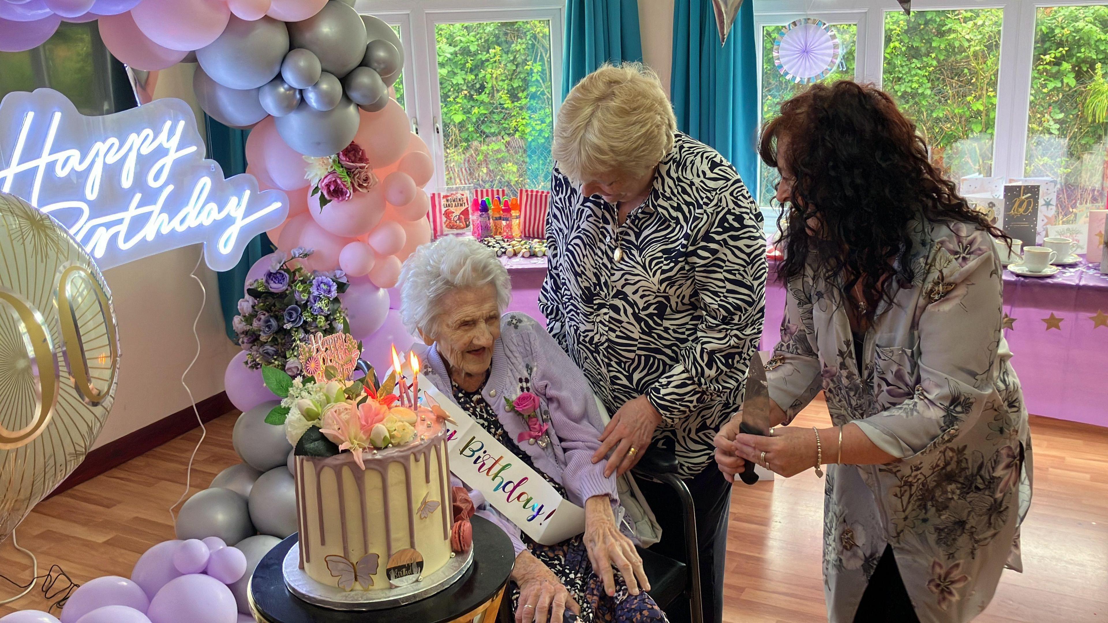 Olive Porritt with two women besides her birthday cake 