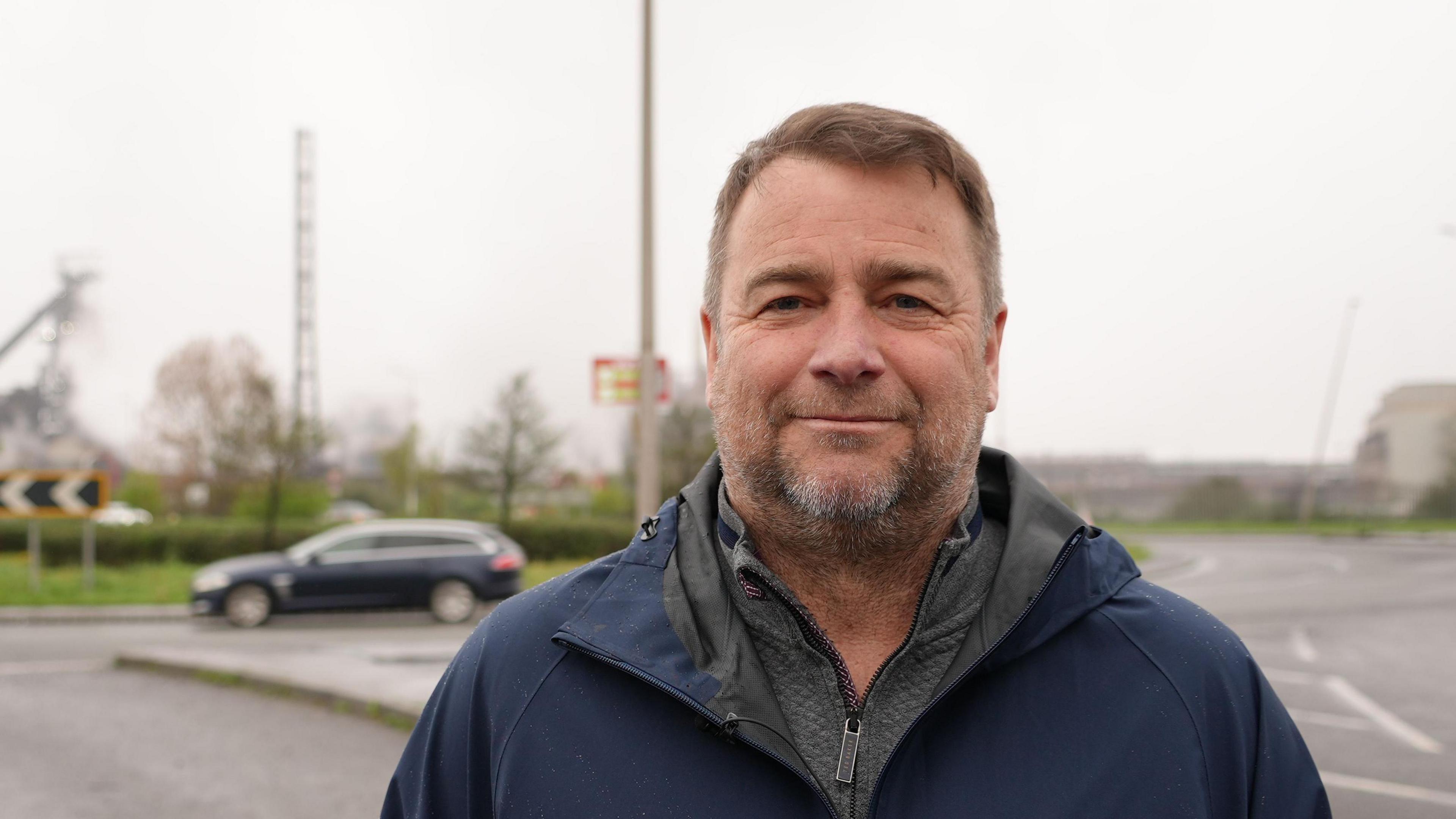 Peter Hughes smiling behind a road 