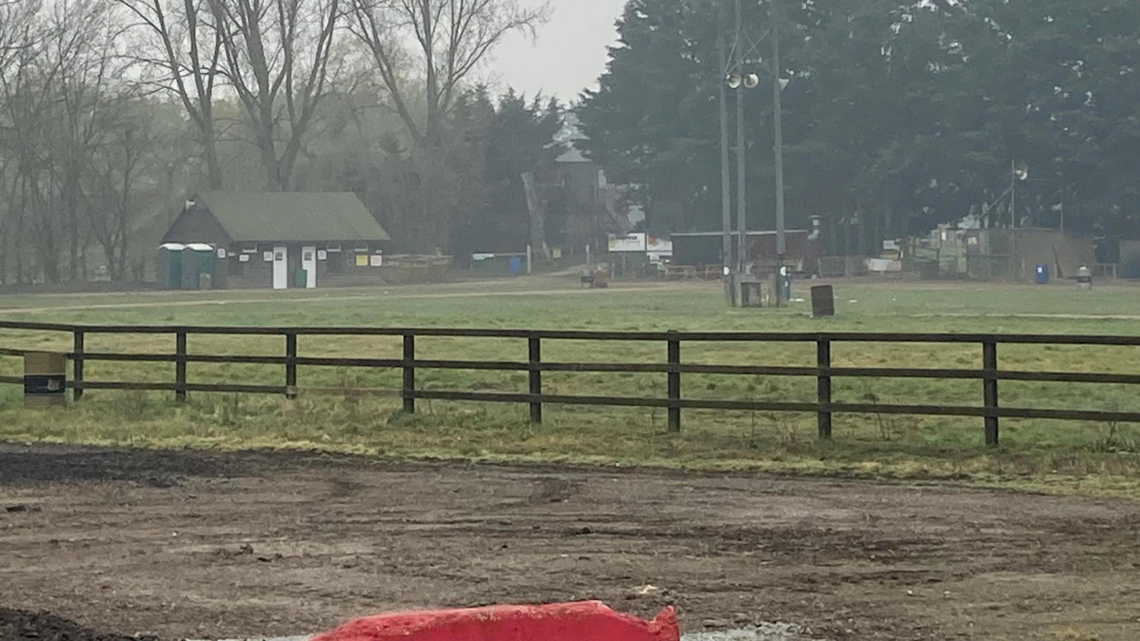 Dirt bike track in a large field. Buildings and trees can be seen in background. 