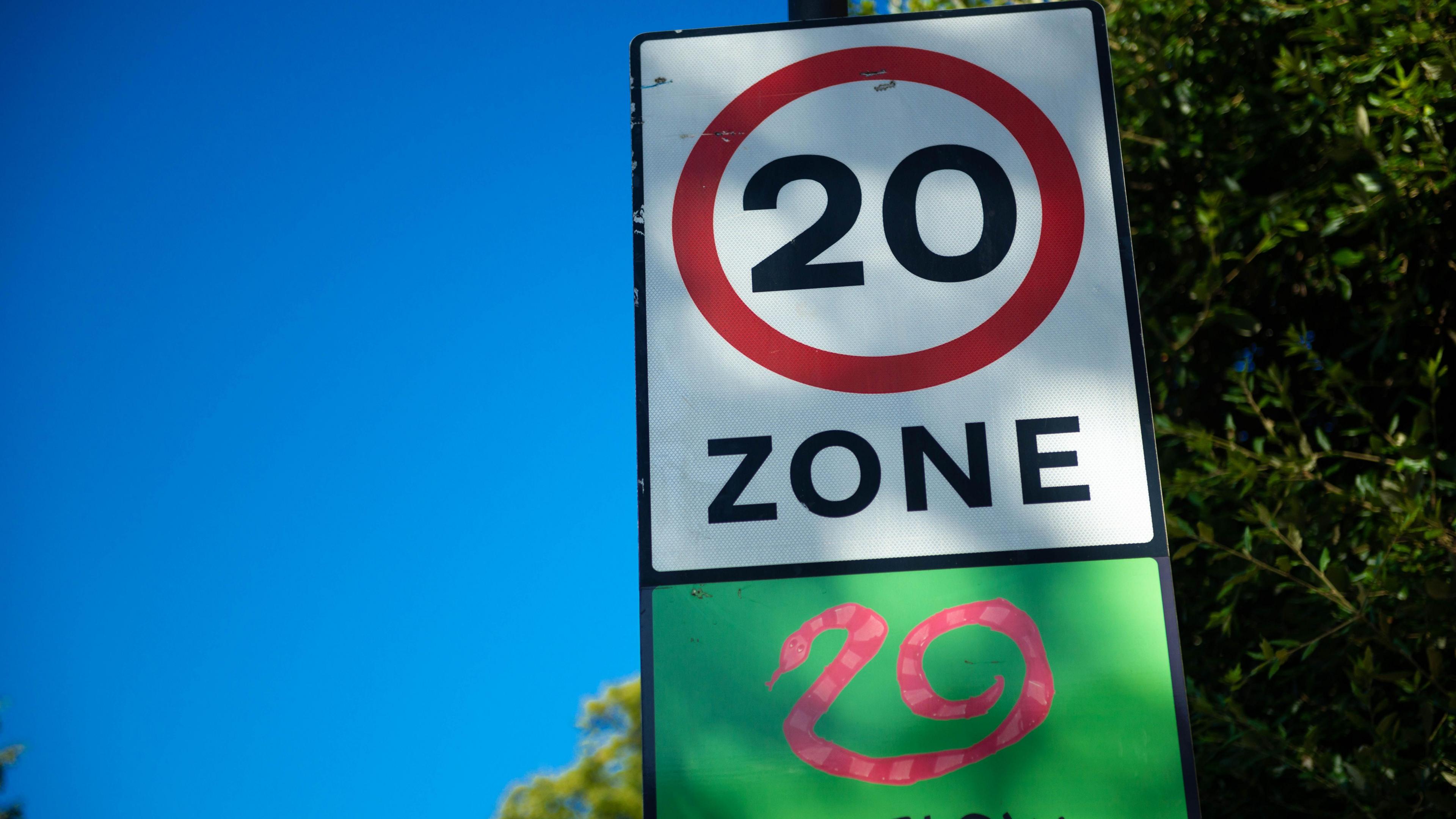 Road sign showing a 20 mph speed limit zone with snake graphic at the approach to a residential area in Fulham