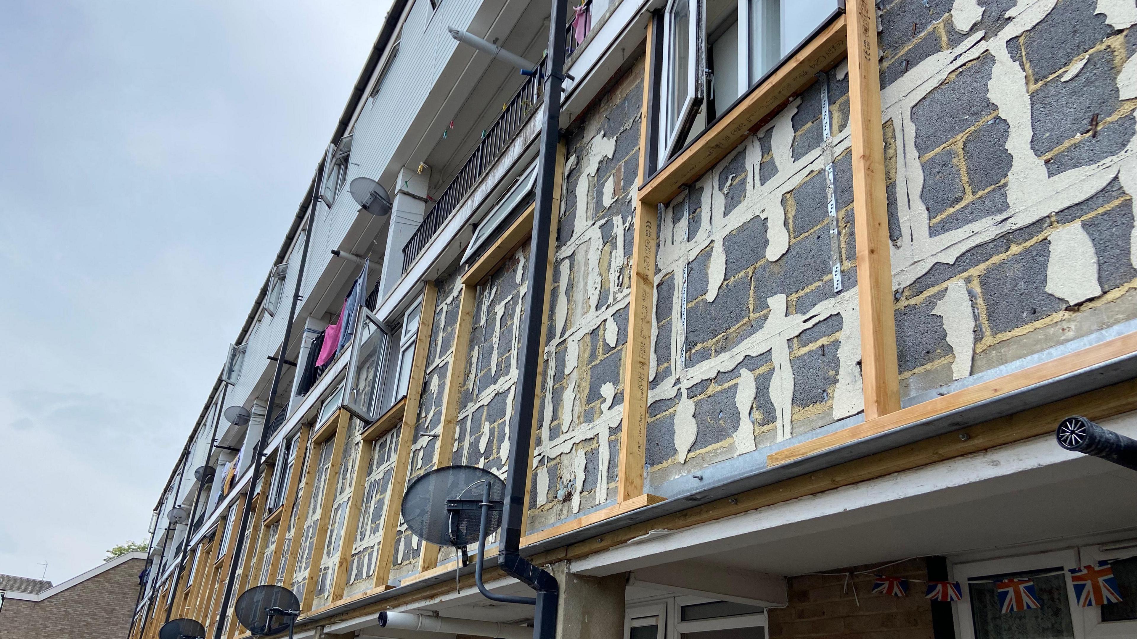 An exposed external wall with patches filled in and timbers in place where the cladding has been removed