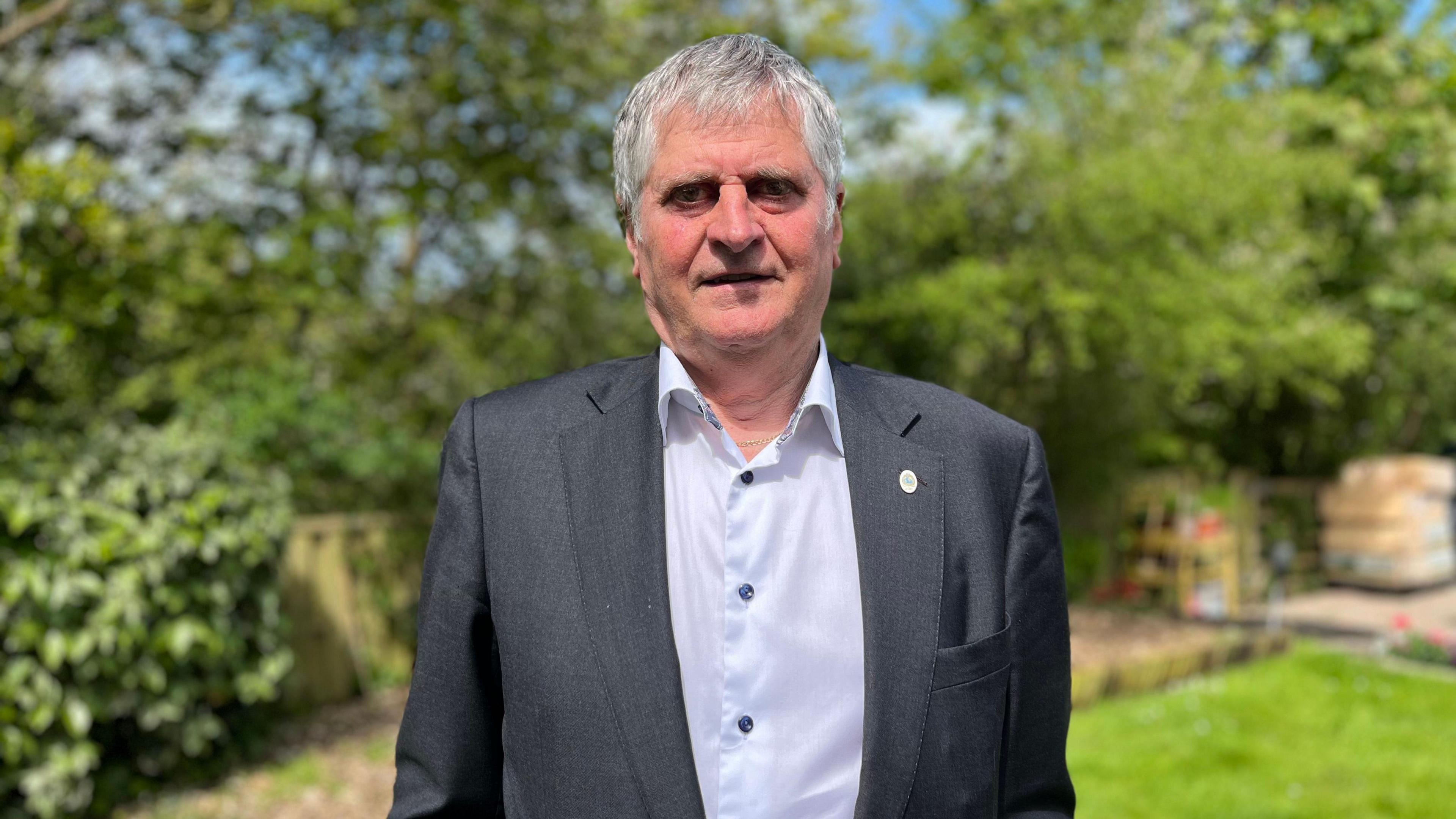 Deputy Rob Prow, he is standing in a garden wearing a suit 