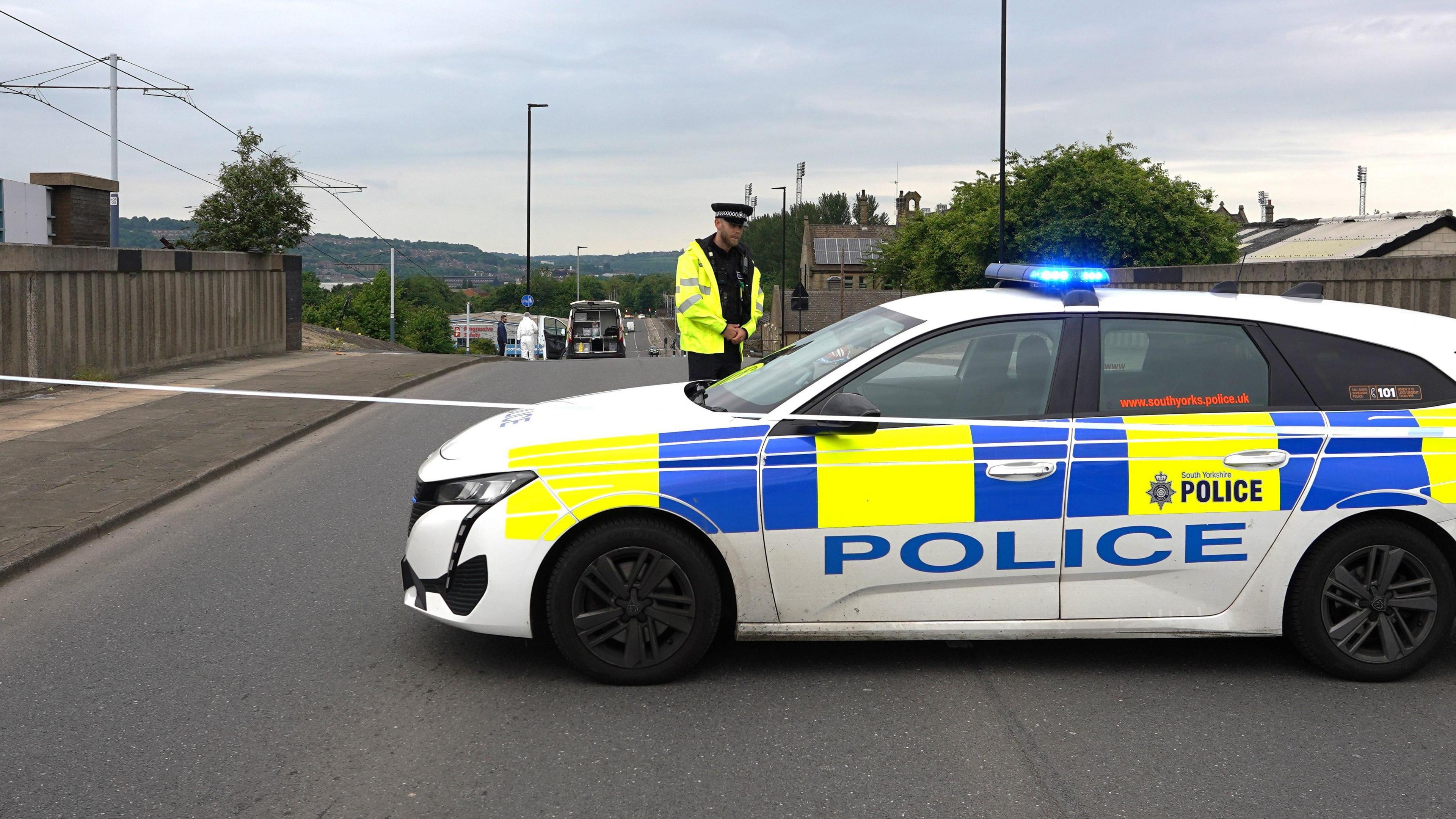 A police officer stands by a police car