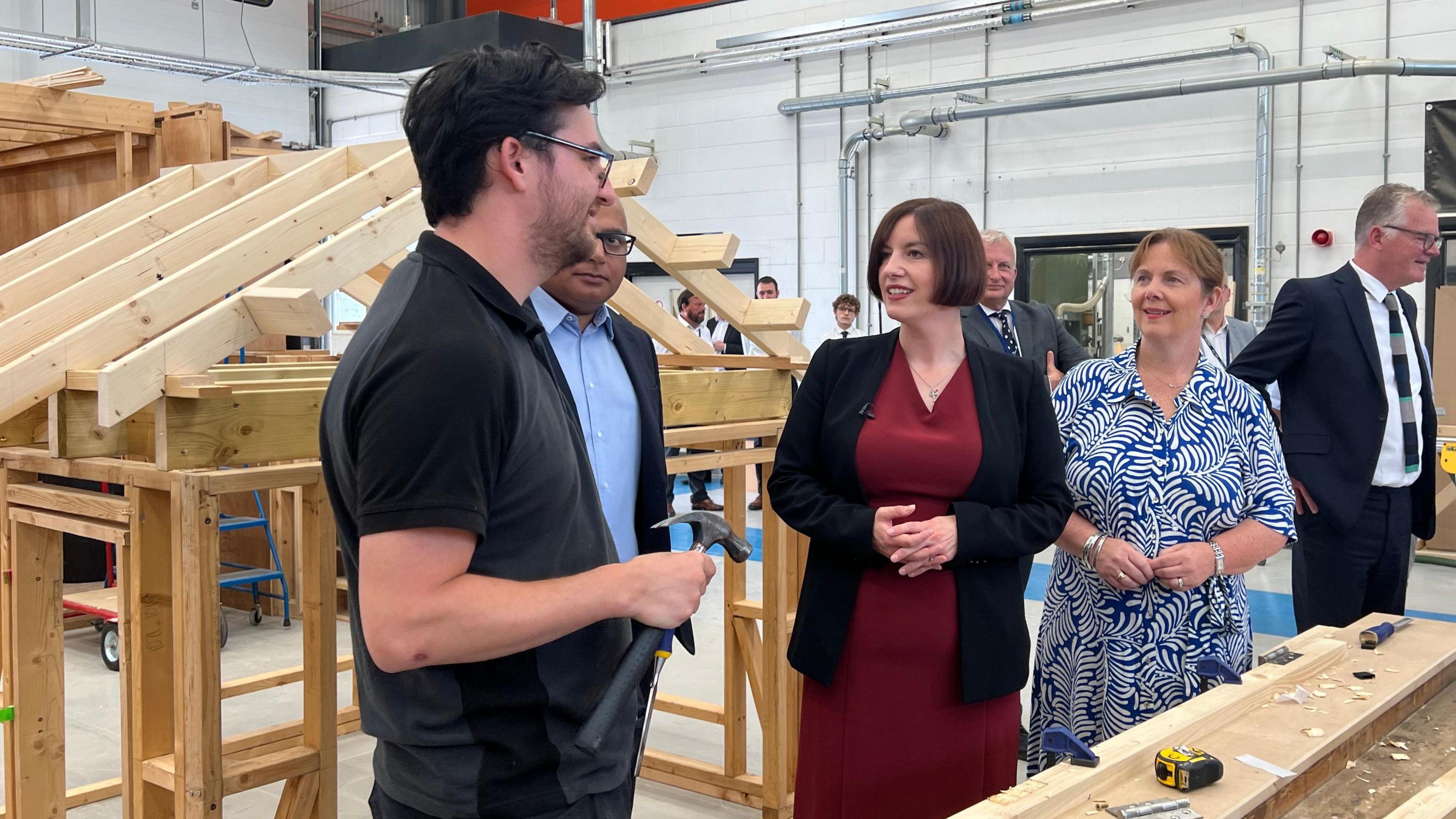 Group of people talking to a male apprentice in a construction workshop