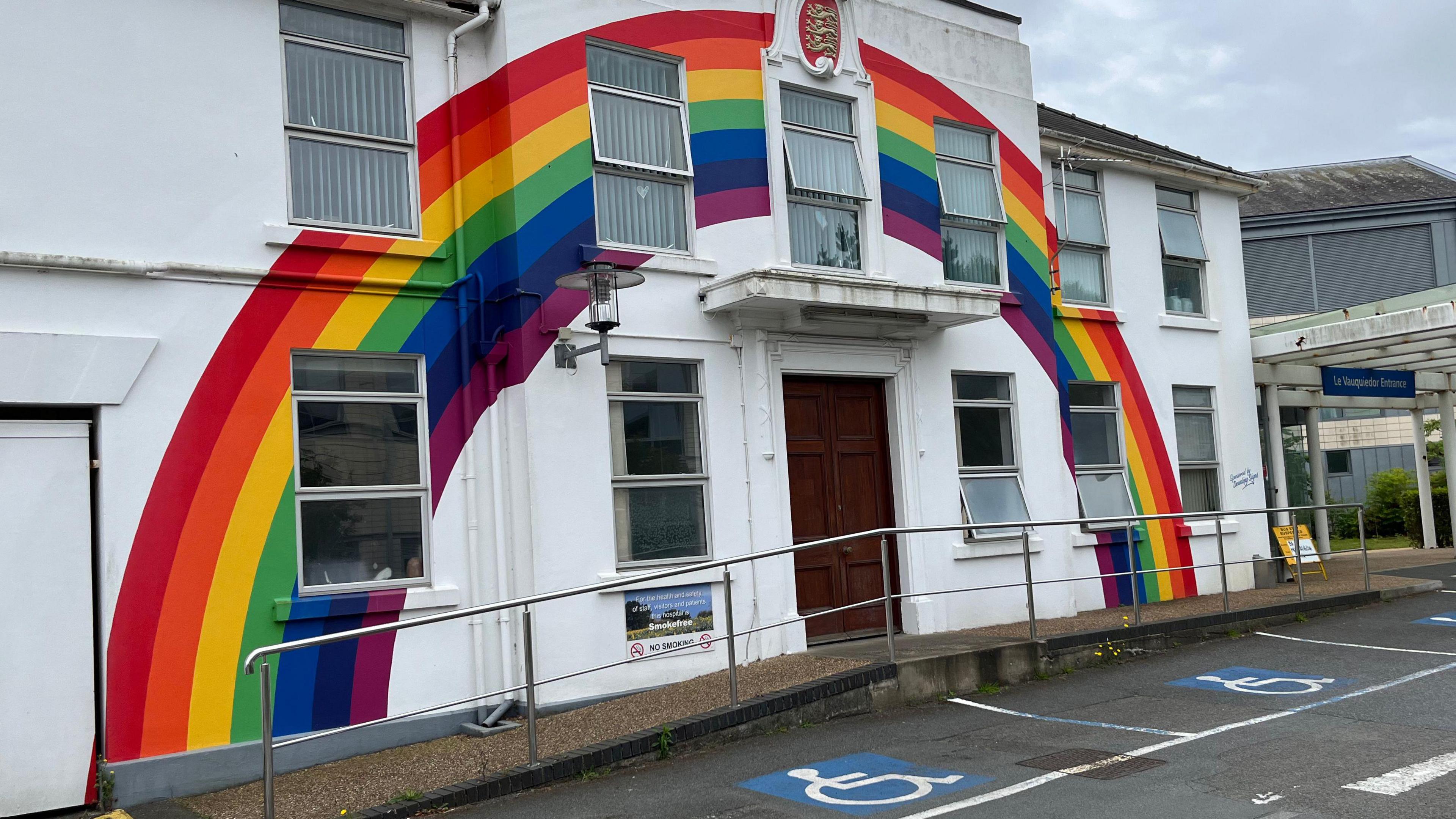 A rainbow painted on a white building. 