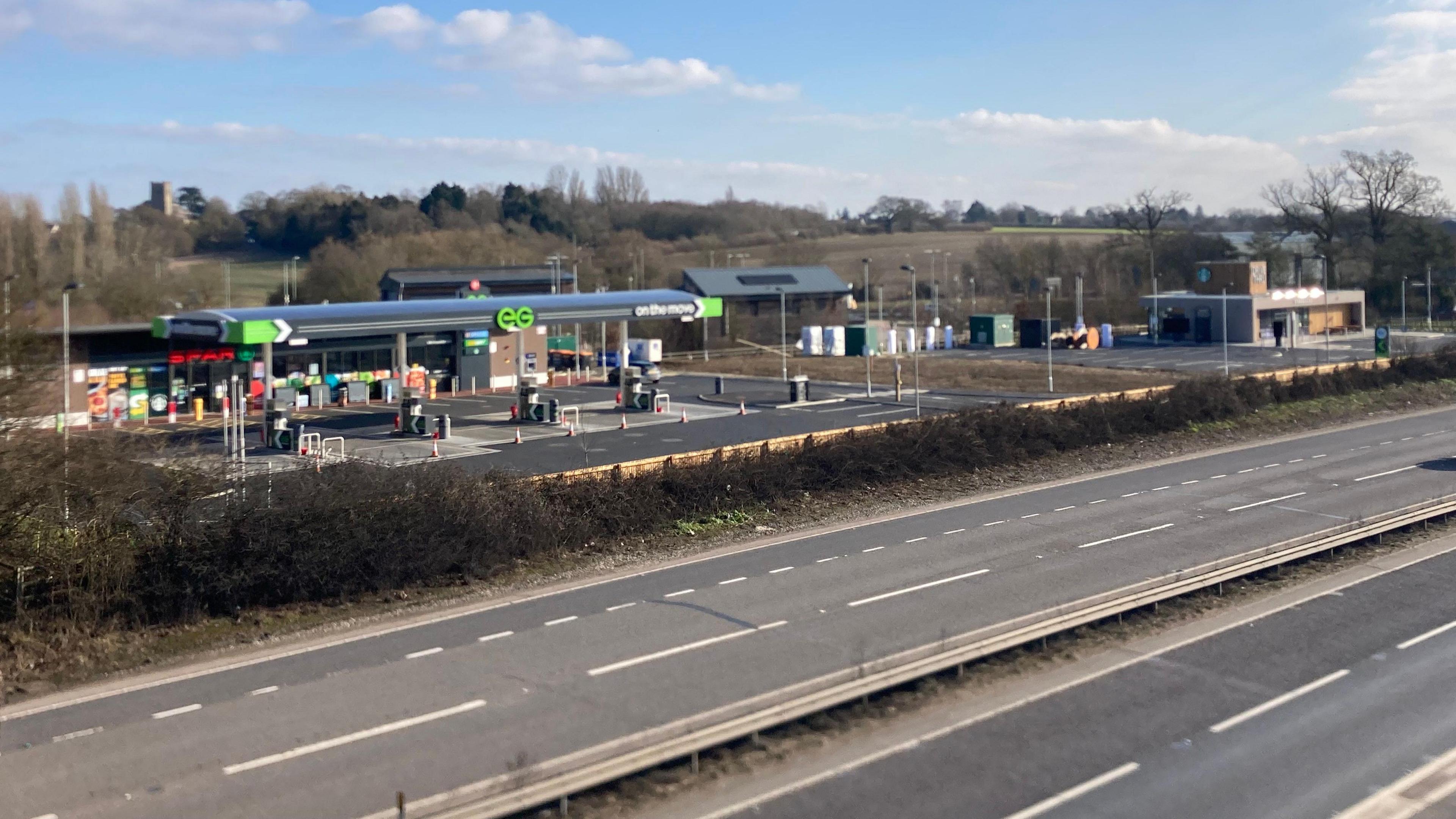 A picture of a petrol station. In front of the petrol station there are roads.