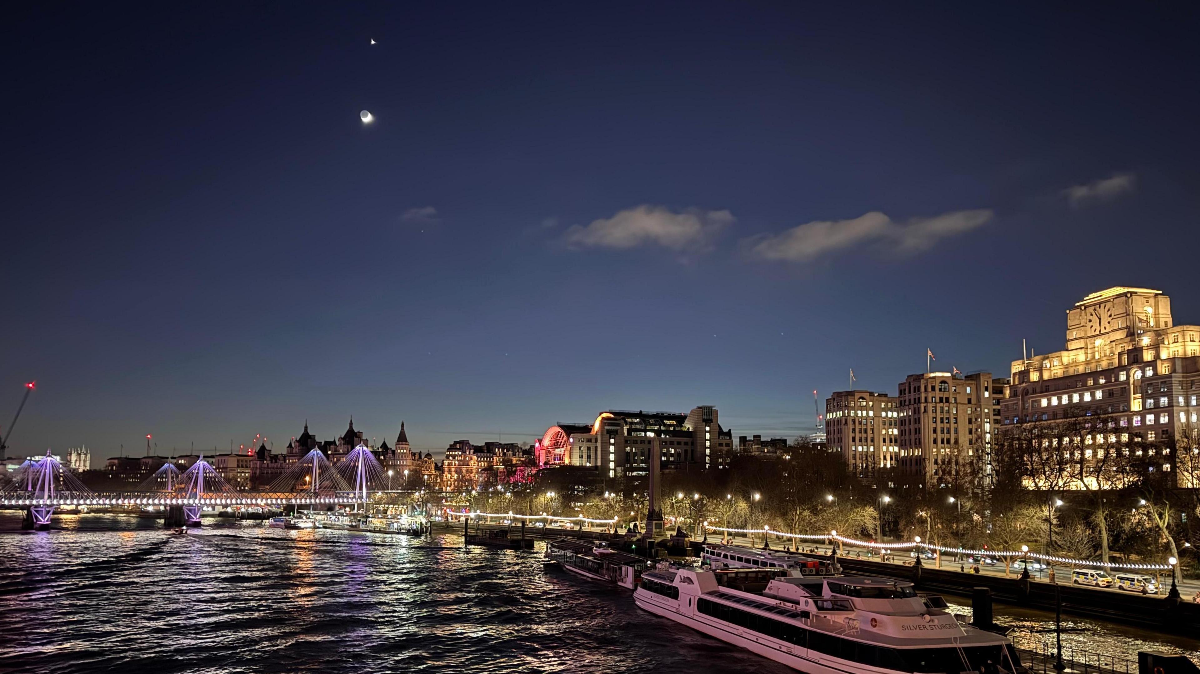 Venus and the Moon are visible in the night sky over the River Thames, which is illuminated by nearby buildings and the Golden Jubilee Bridge.