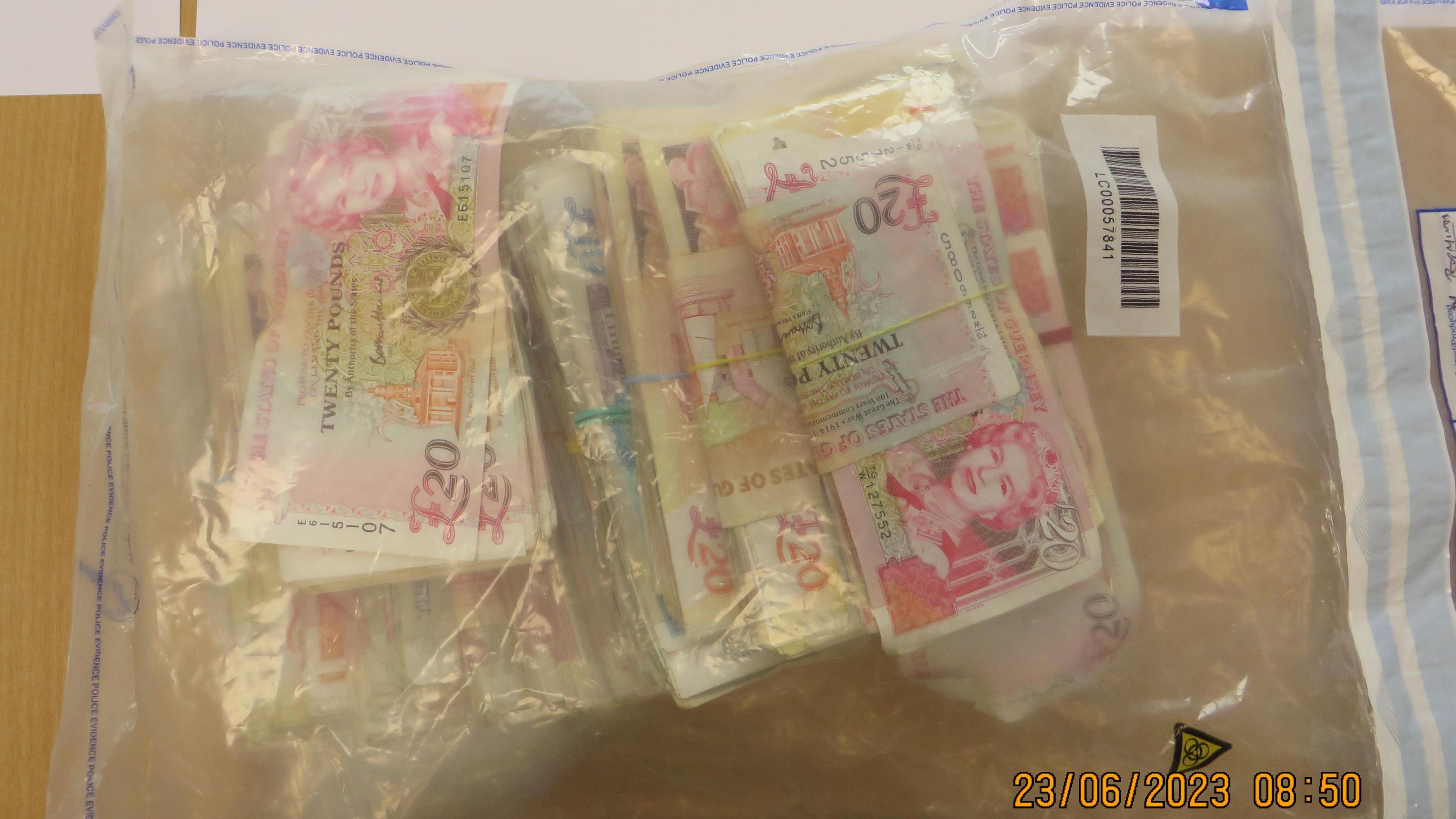 A ziplock transparent plastic bag in which bundles of £20 notes are held with elastic bands. There is a date stamp on the photo which reads 23.06.2023 08:50