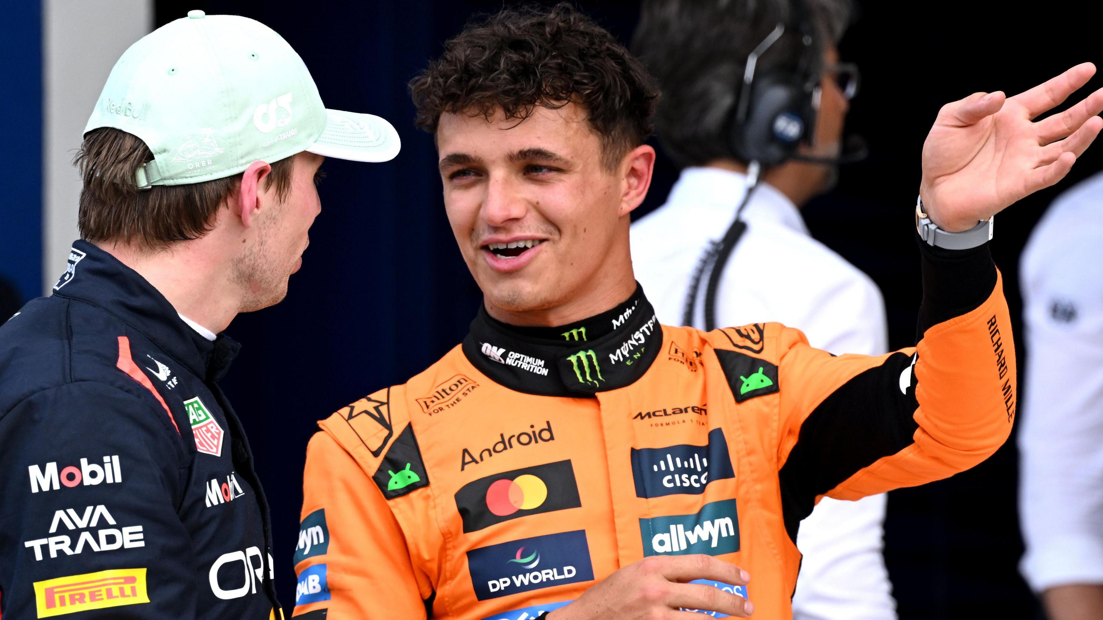 Lando Norris smiles and gestures with his left hand while talking to Max Verstappen after Miami Grand Prix qualifying