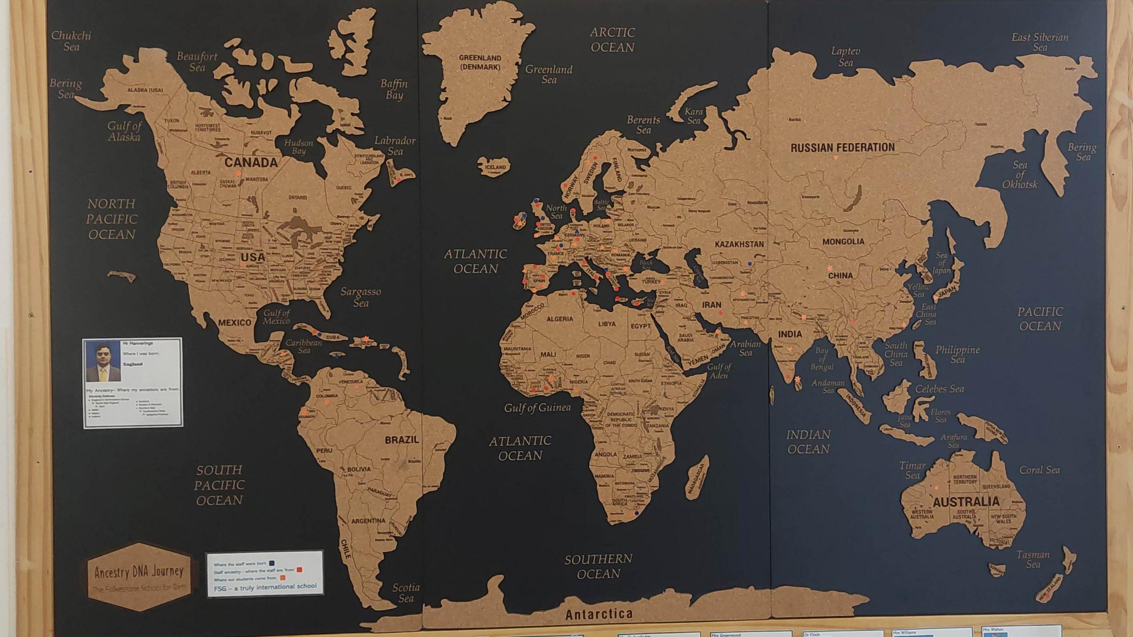 A black and gold map of the world with the teachers' roots drawn on it