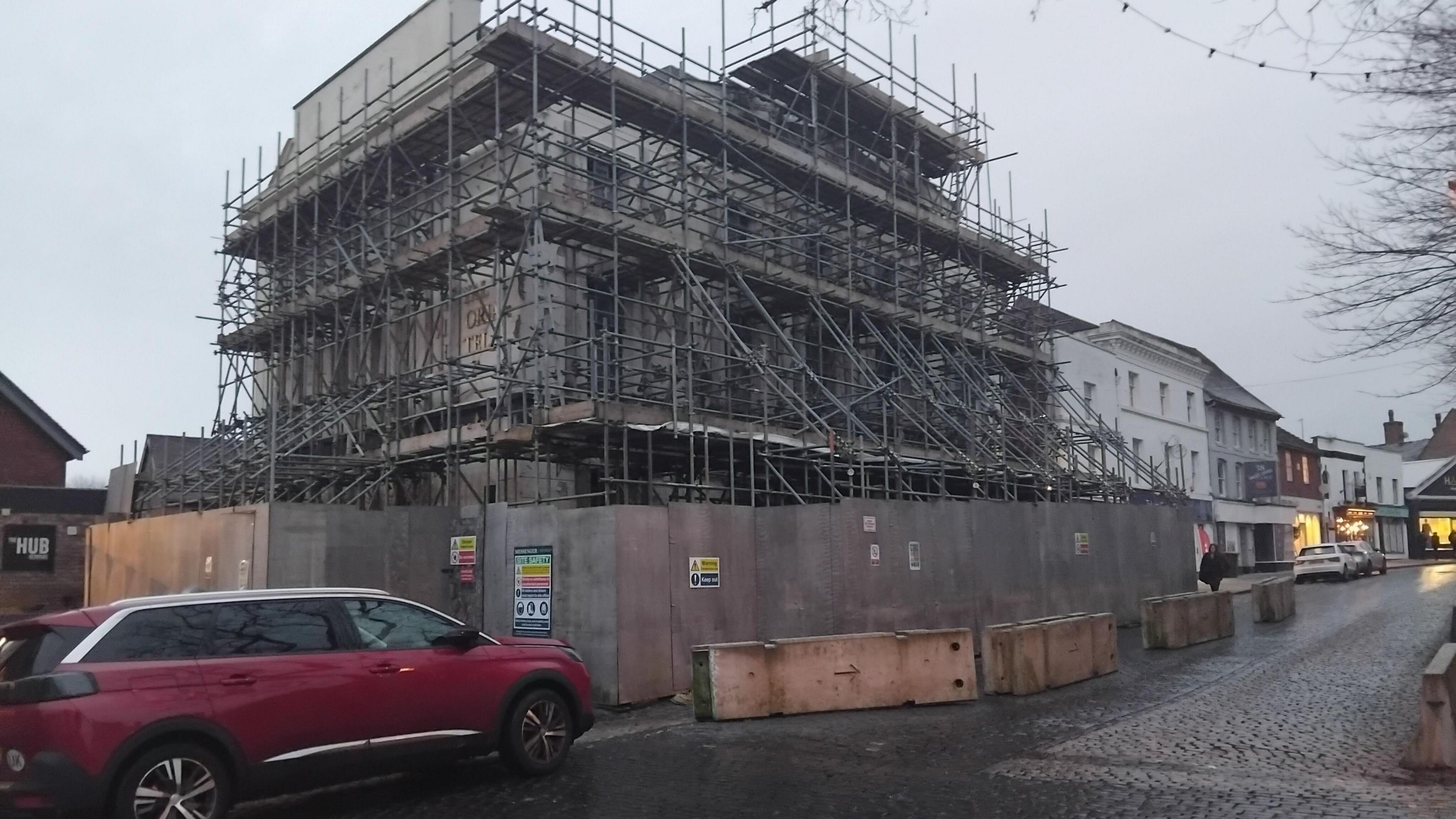 The large hotel building is covered in scaffolding in Newport. There is a red car parked in front and the sky is grey.