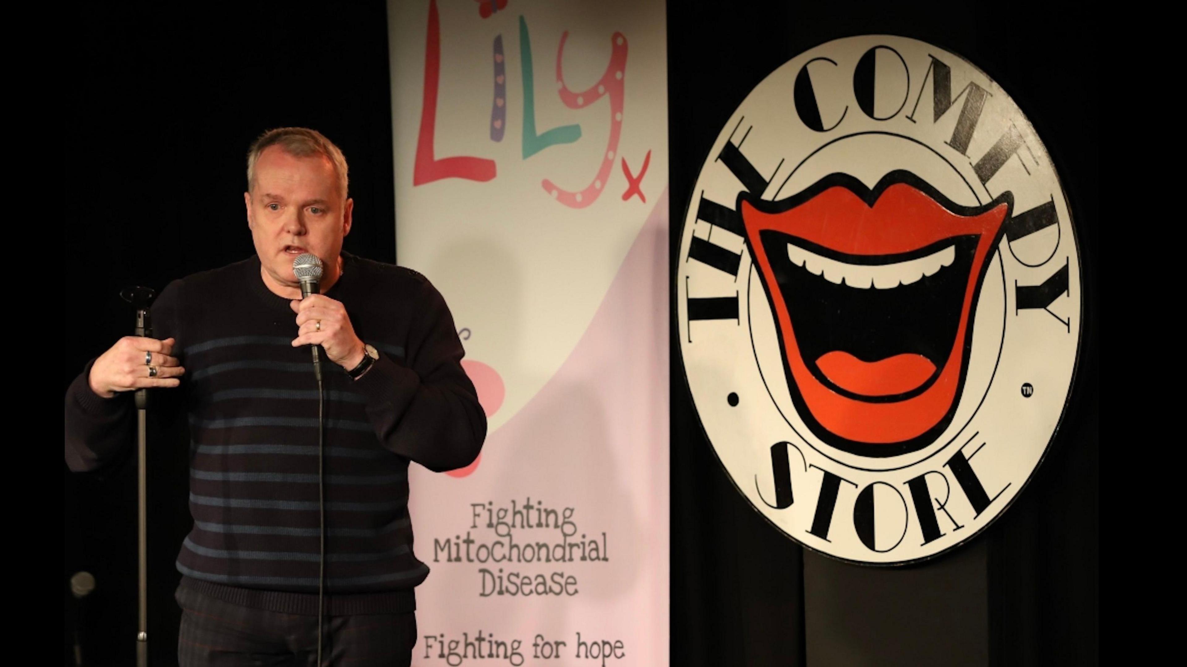 Kevin Day on stage with a Lily Foundation banner behind him.