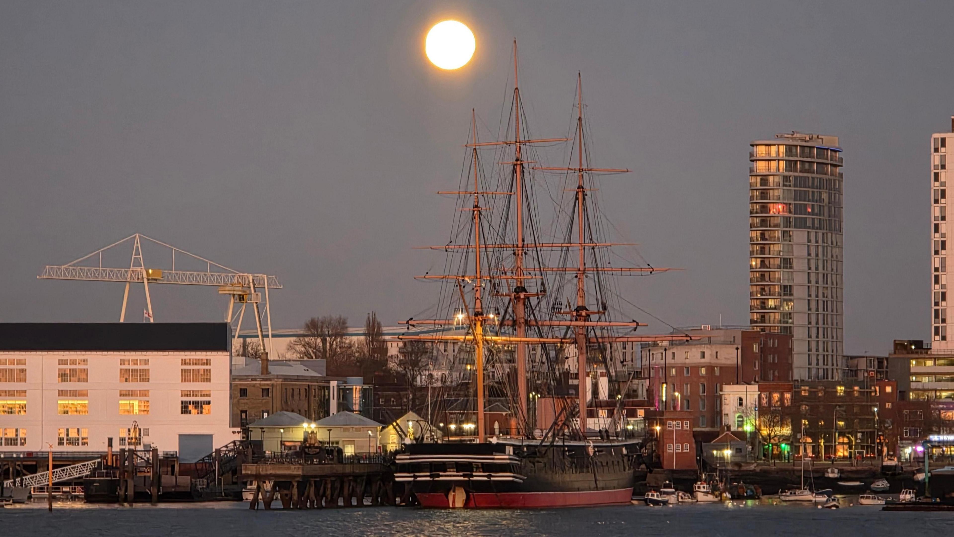 Wolf moon illuminates a tall ship docked at a port in Hampshire 