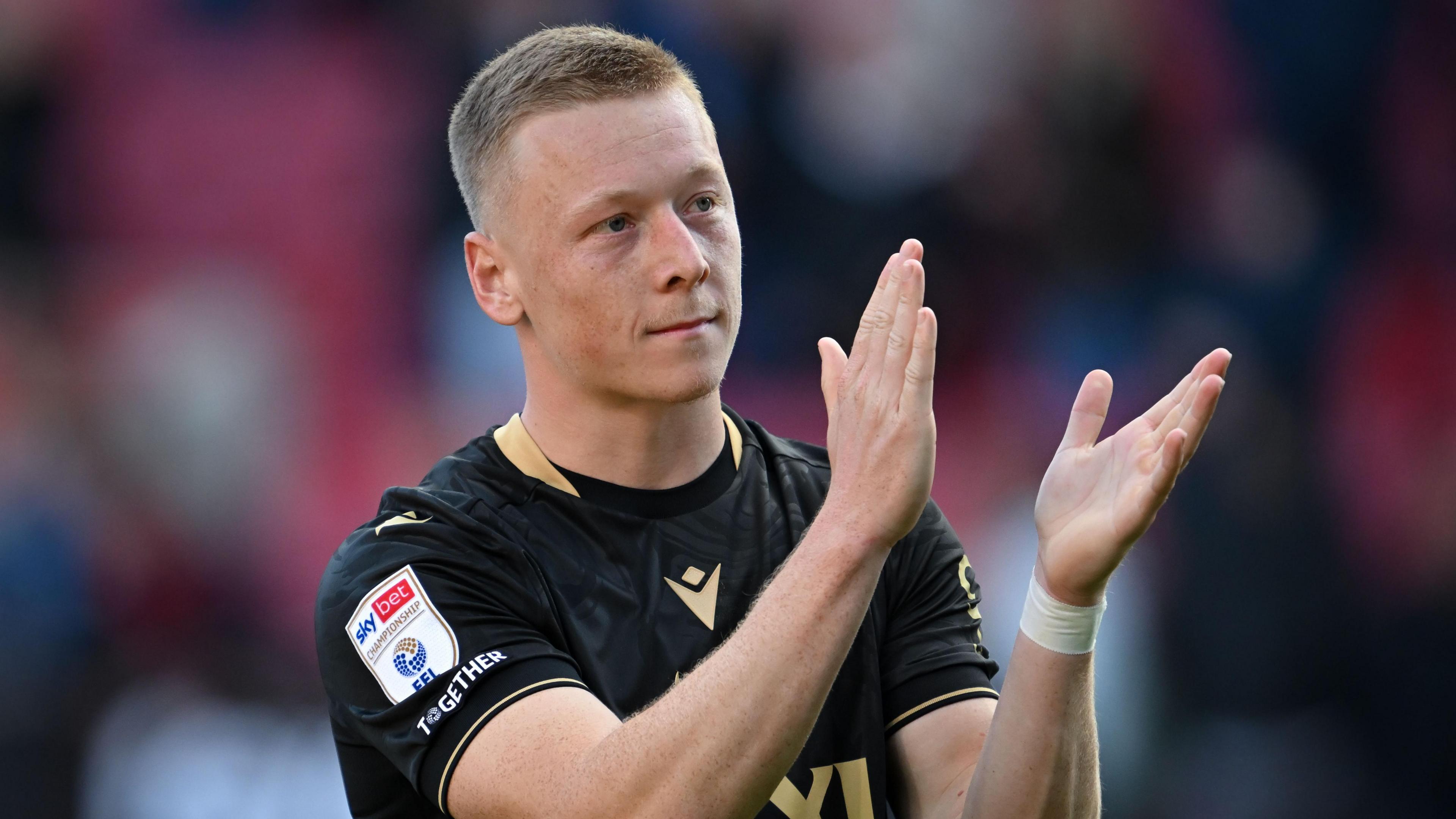 Oxford United midfielder Brian De Keersmaecker wearing away dark kit clapping fans 