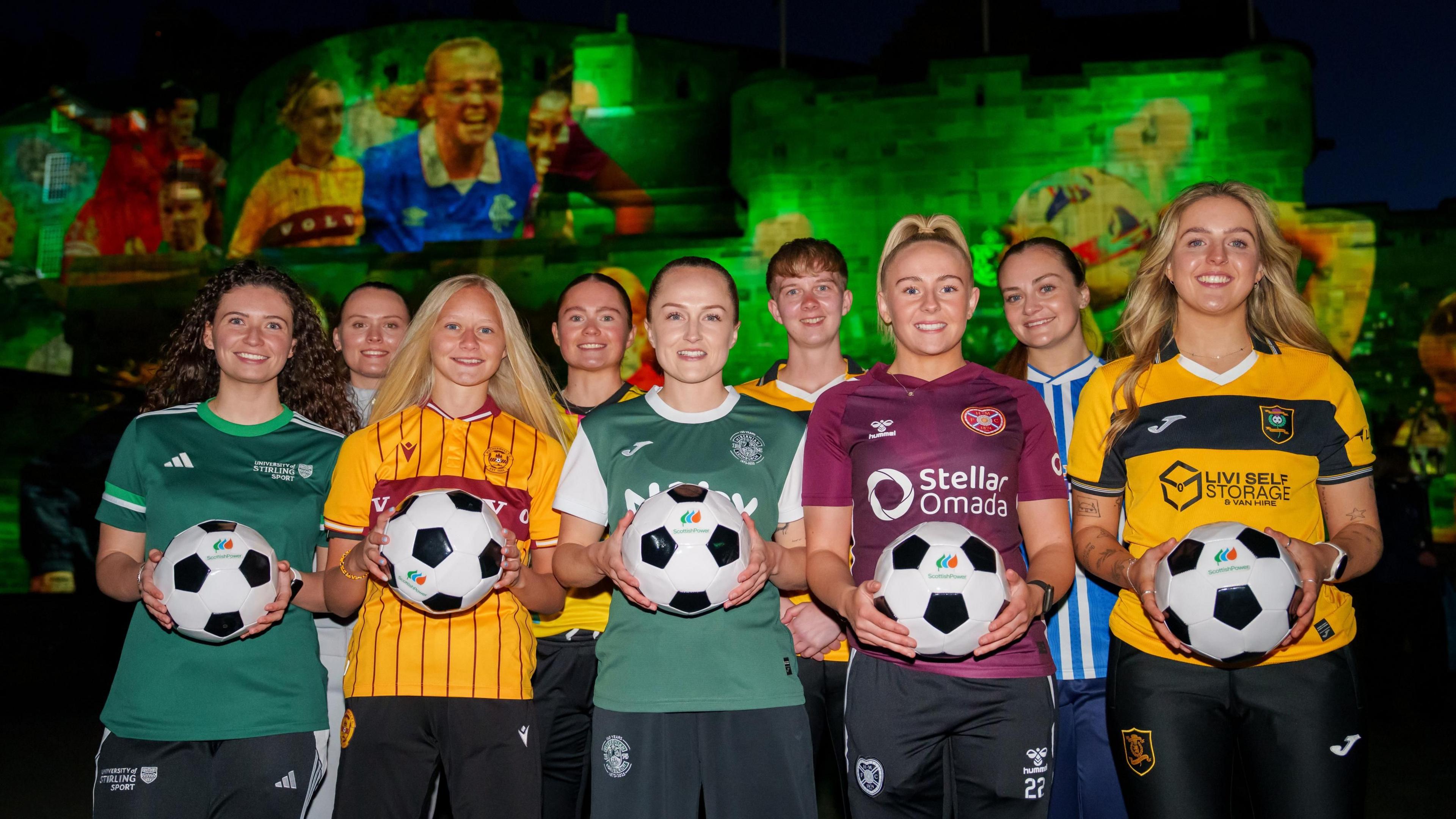 Scottish Women's Premier League players hold footballs and smile at the camera at an event hosted by ScottishPower in Edinburgh Castle.
