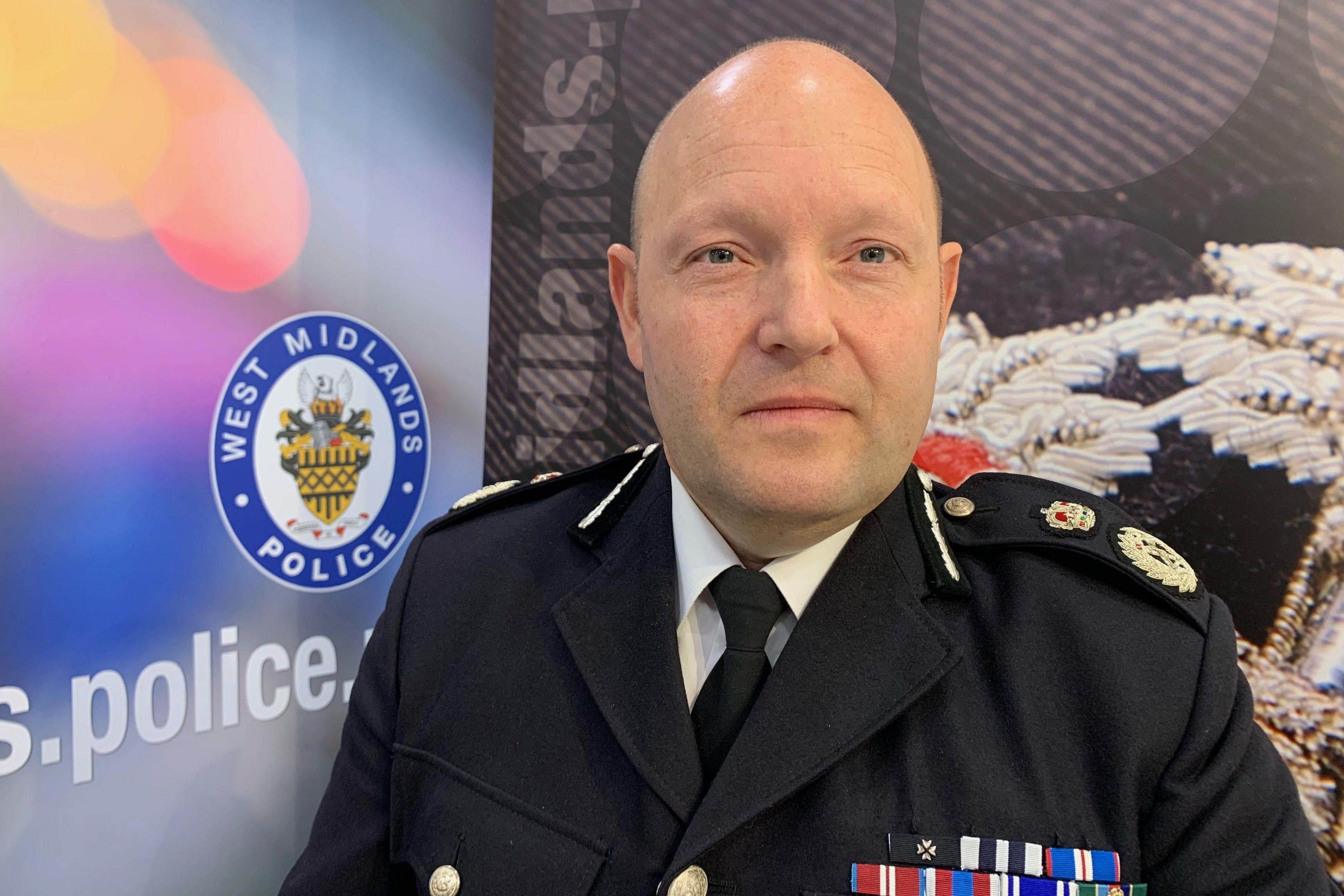 Chief Constable Craig Guildford, of West Midlands Police, at the police headquarters in Birmingham, wearing a police uniform. He is clean shaved and has a shaved head and wears a police uniform of a dark blue jacket with badges on the shoulder and a string of medal ribbons on his left breast.