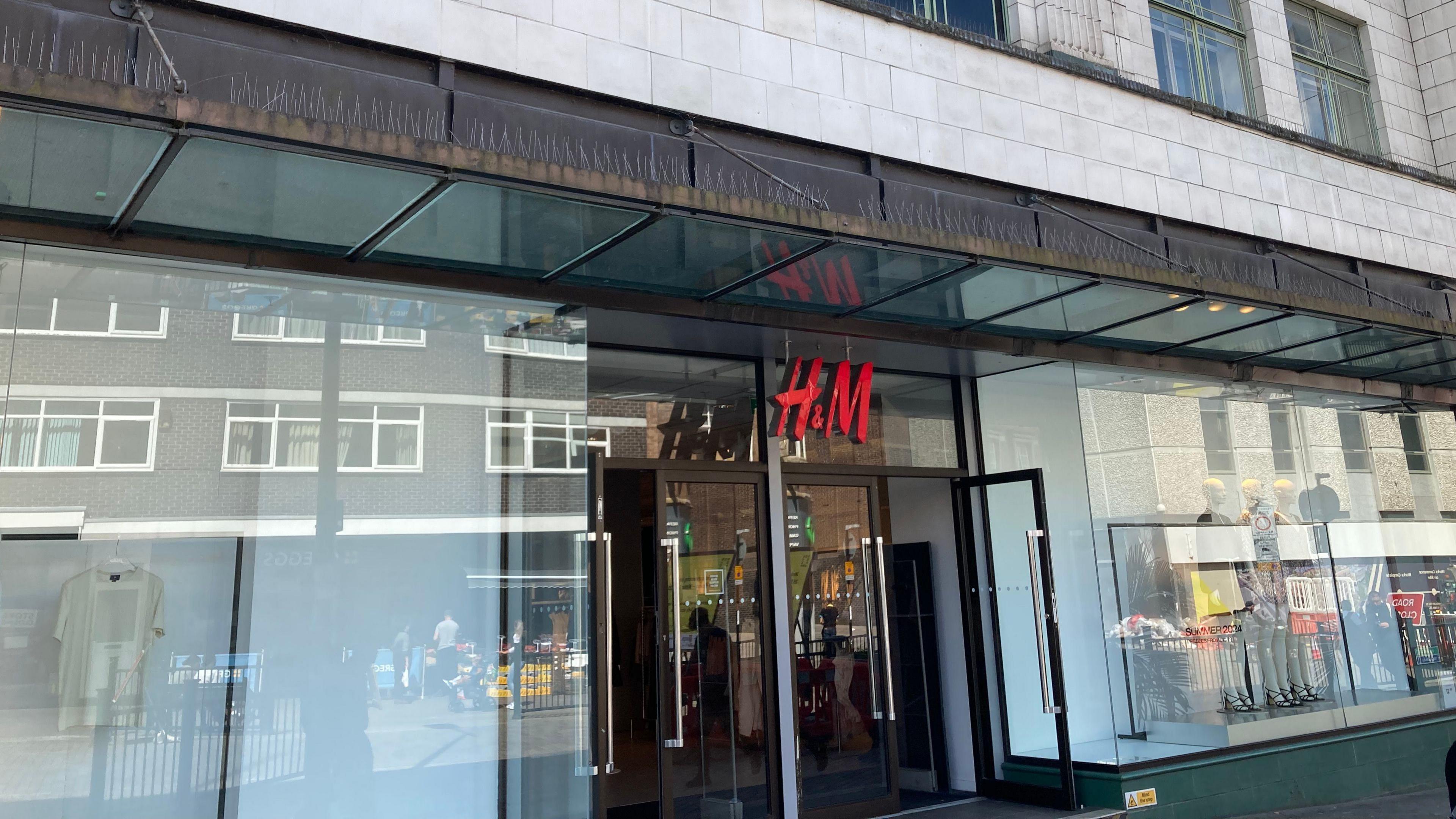 A glass store frontage with the red H&M sign above the two glass open doors.