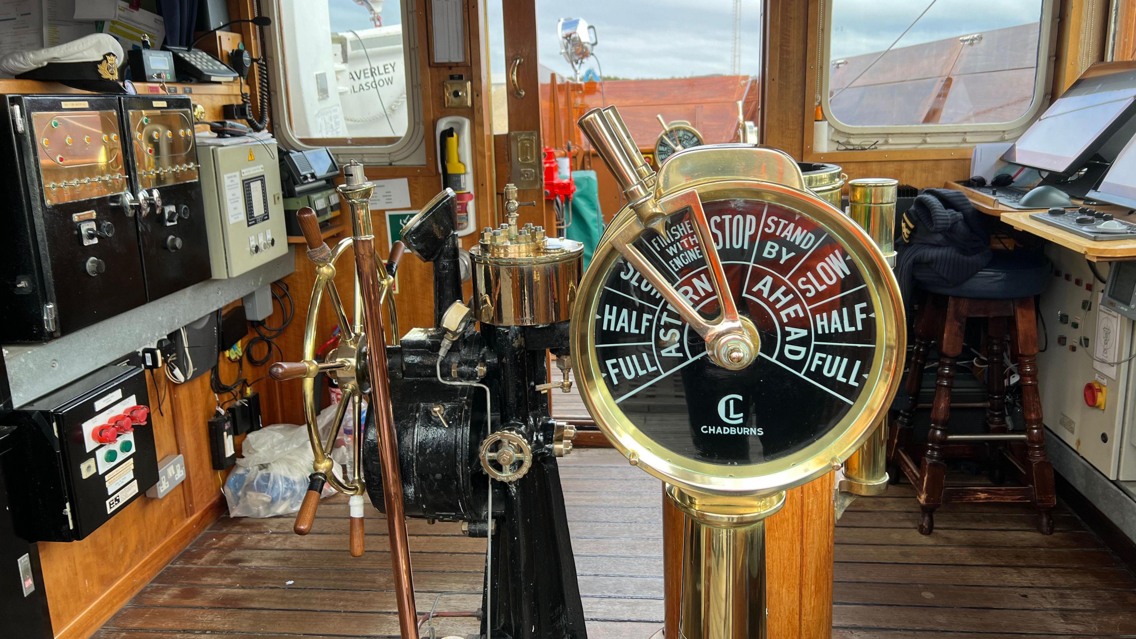 The wheelhouse of the ship, with golden steering wheel and other machinery 