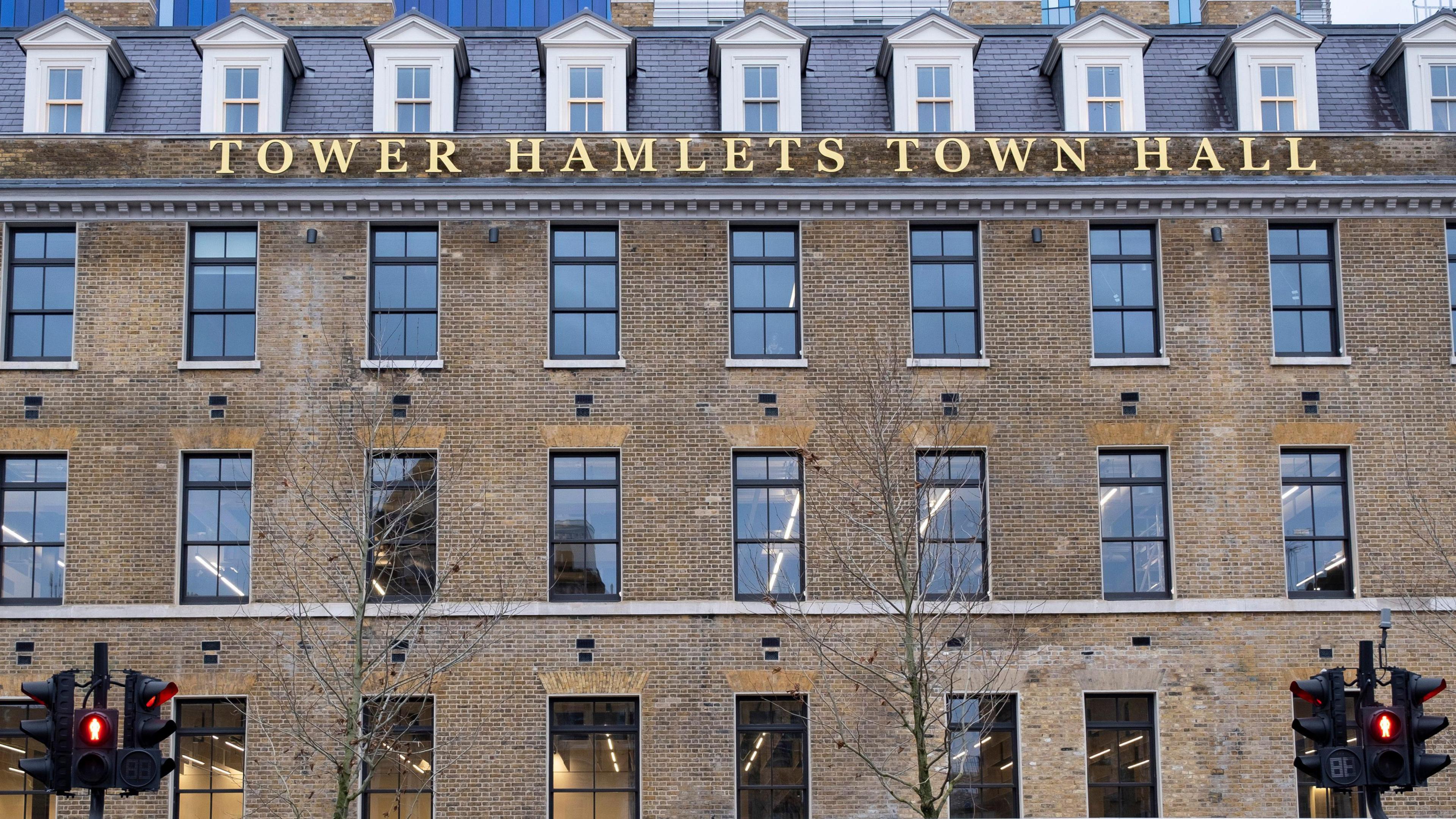 Gold lettered 'Tower Hamlets' sign adorns brick-builty Tower Hamlets Town Hall in London