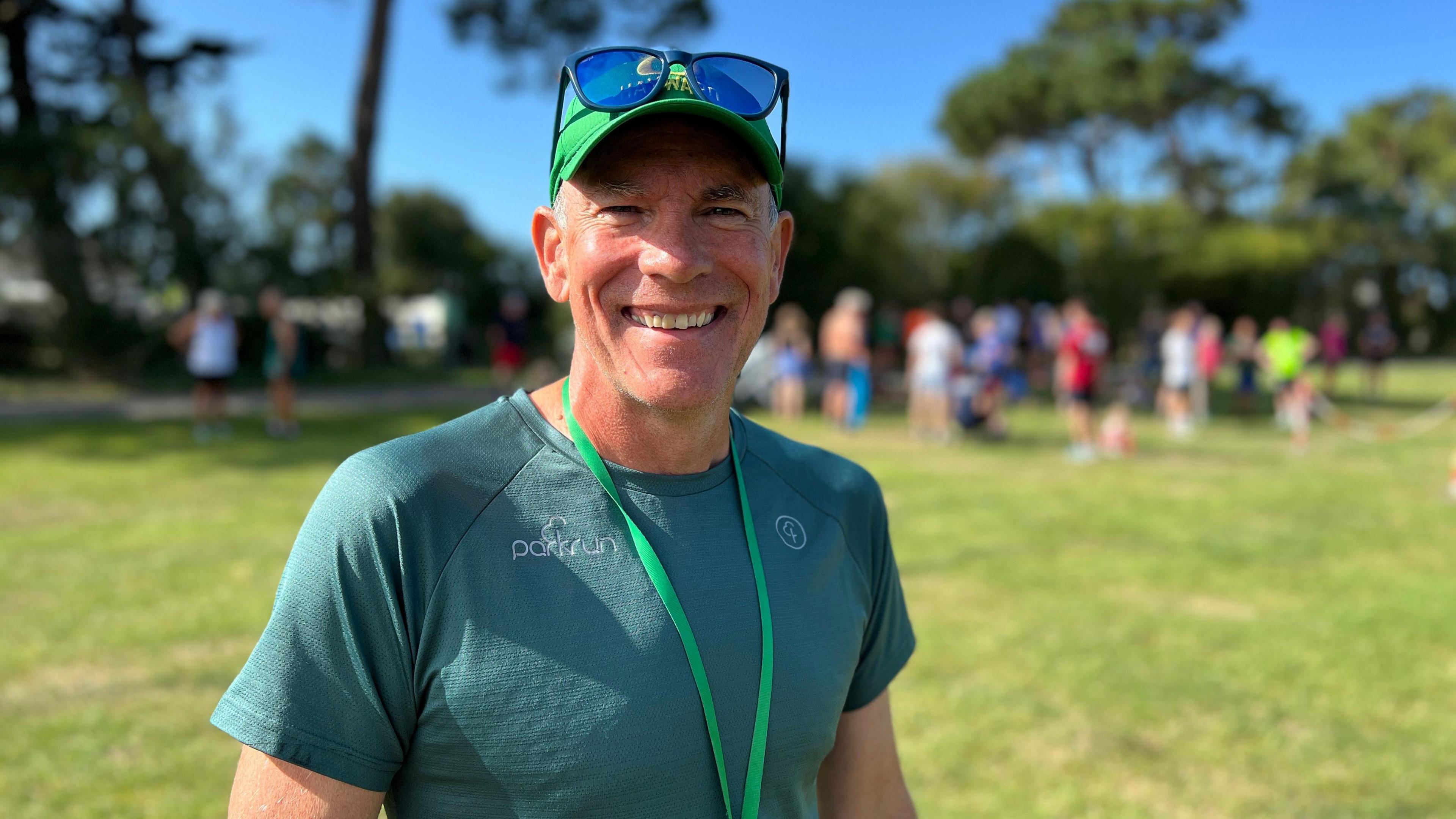 Michael smiles at the camera as runners rest behind him after they finished running