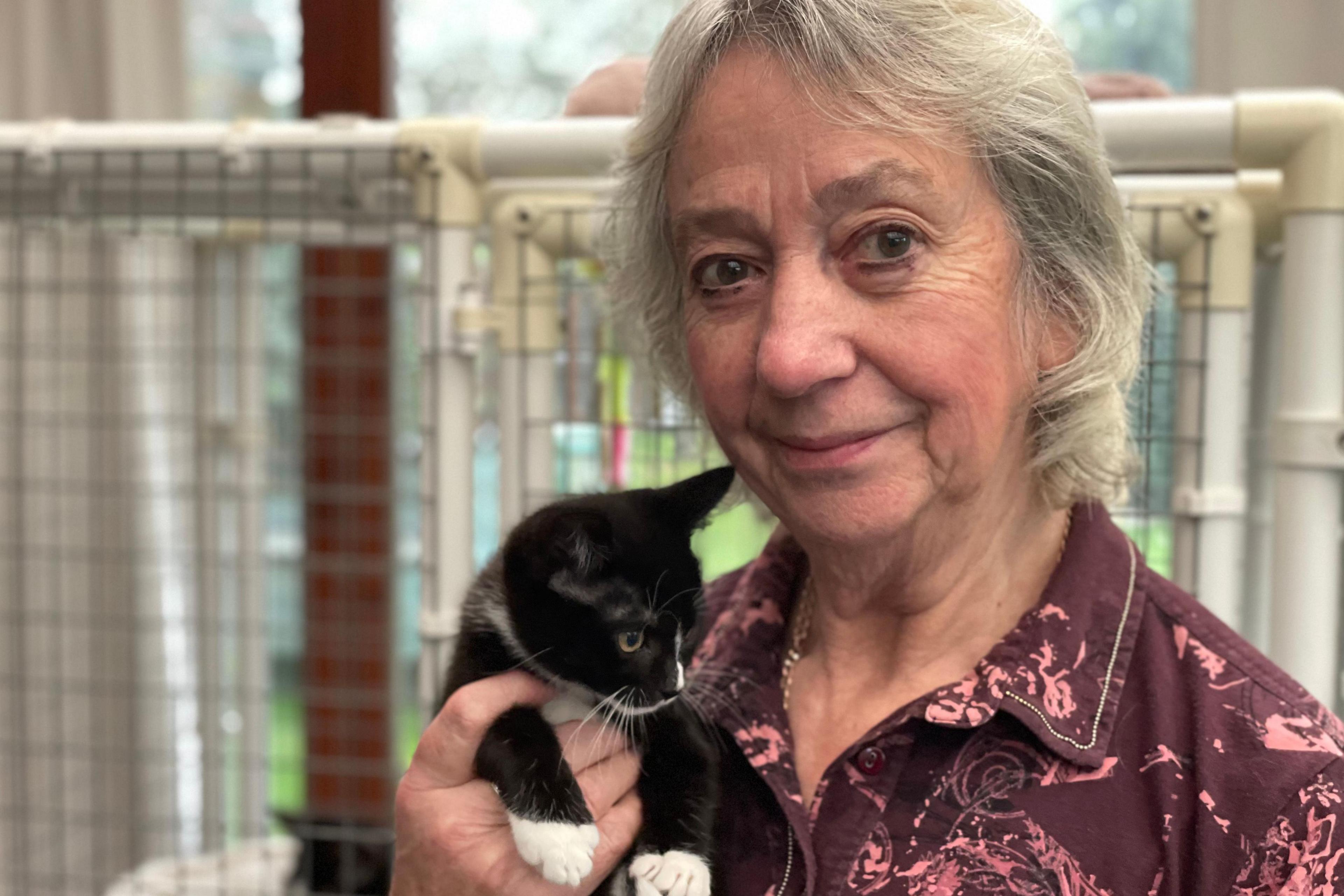 Penny smiling at the camera holding jerry the kitten in her hand