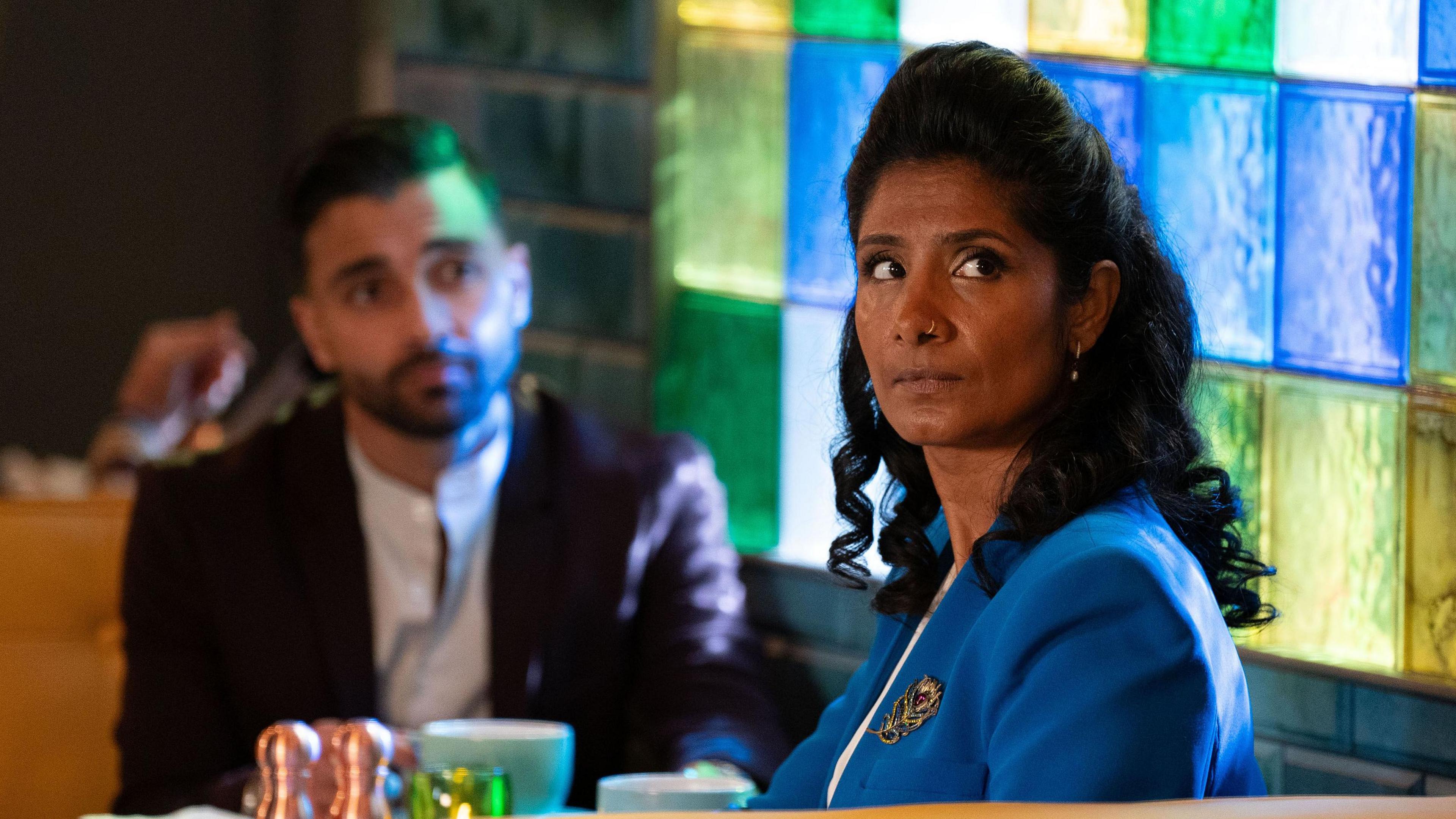 Vinny (Shiv Jalota) and Suki (Balvinder Sopal) in EastEnders, sitting at a cafe table.