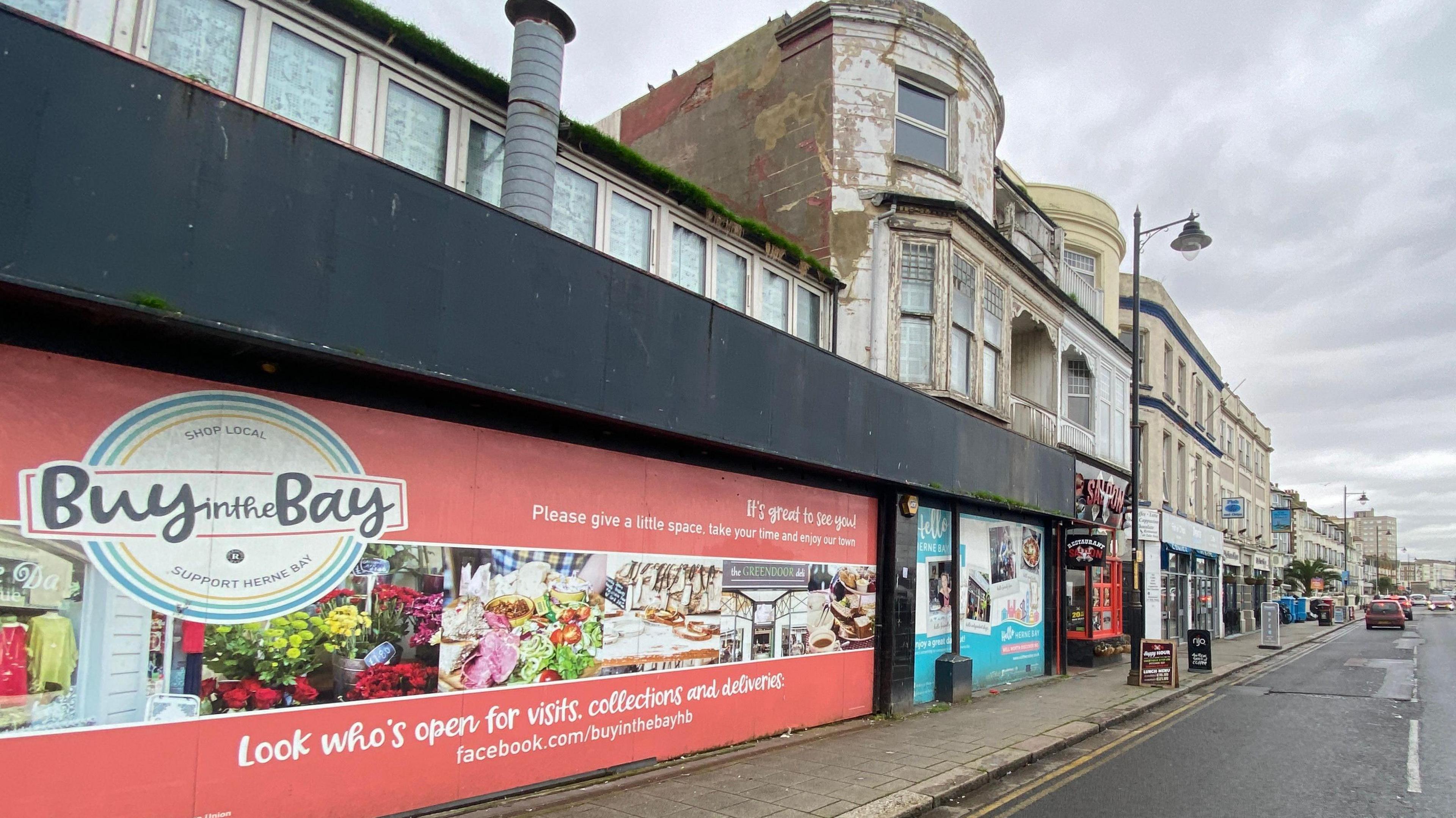 A rundown shop frontage with a sign urging people to "buy in the Bay" 