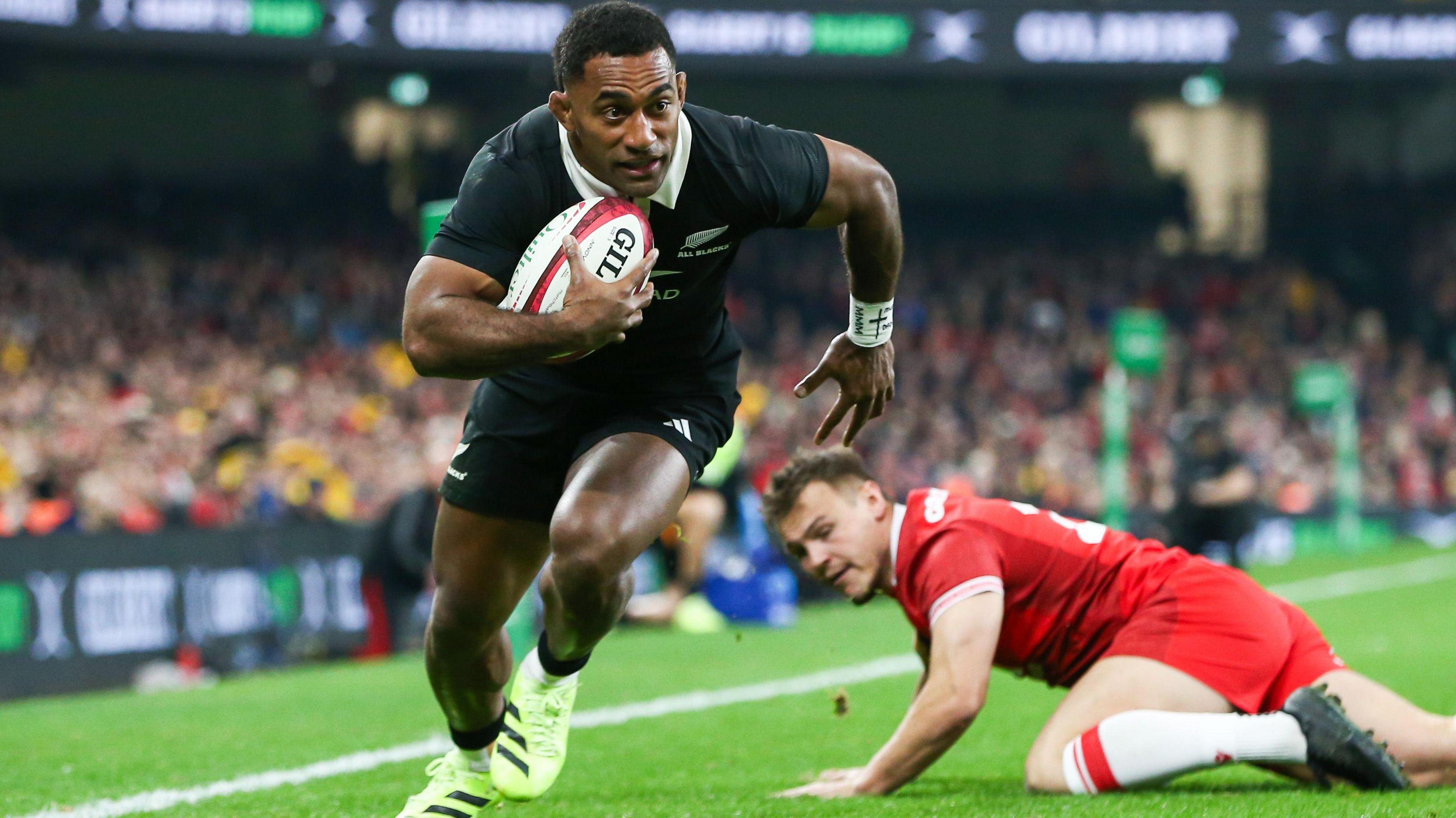 Sevu Reece runs in a try for New Zealand as Jarrod Evans looks on