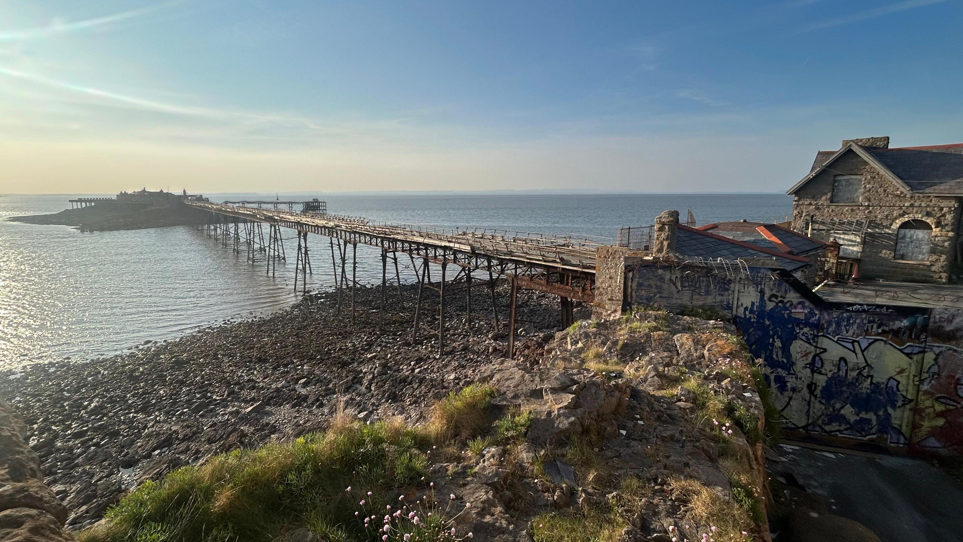 A view of Birnbeck Pier with the tide out. The pier is derelict, as are the buildings near it