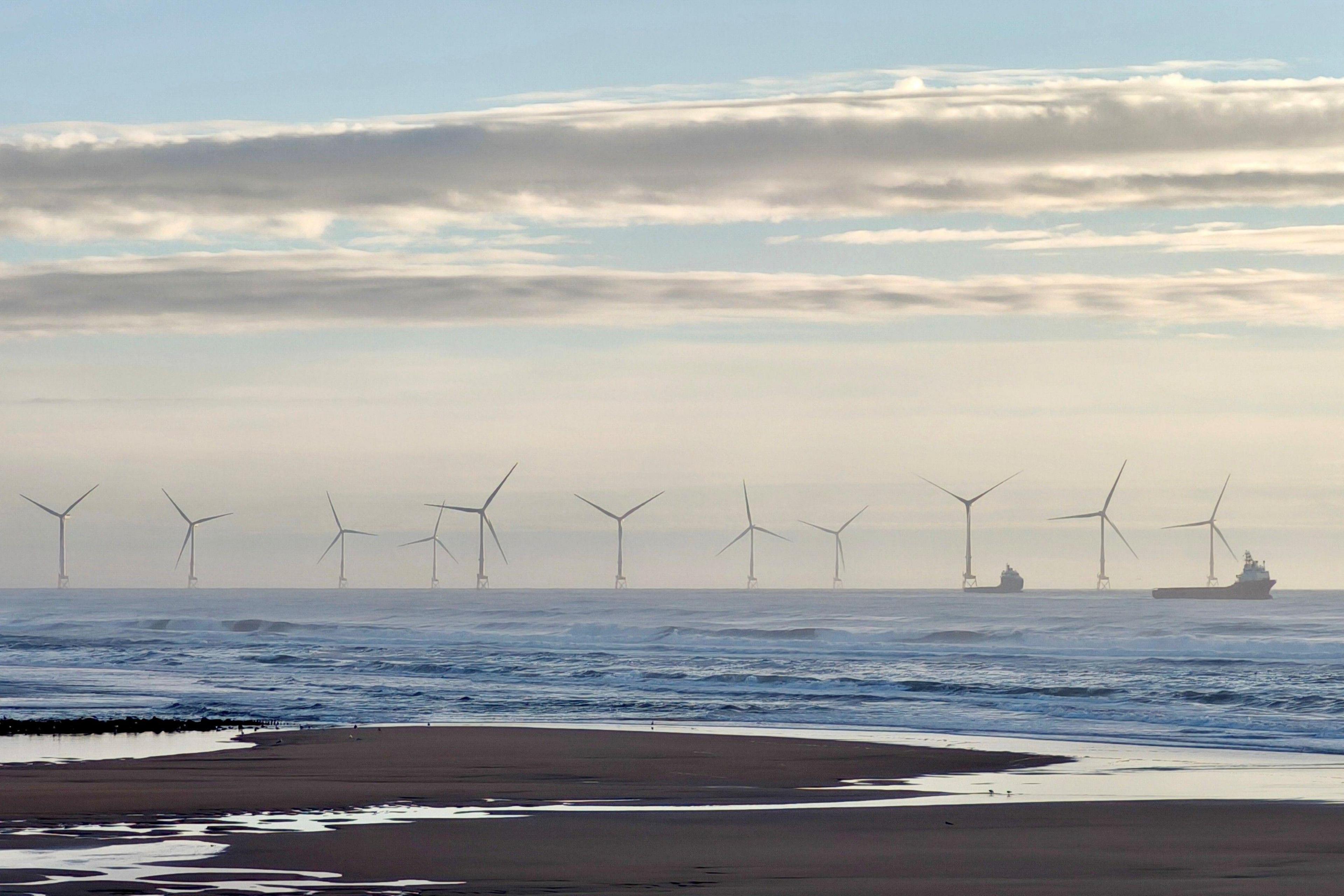 Aberdeen beach, sand in foreground, wind turbines and offshore supply vessels in distance.