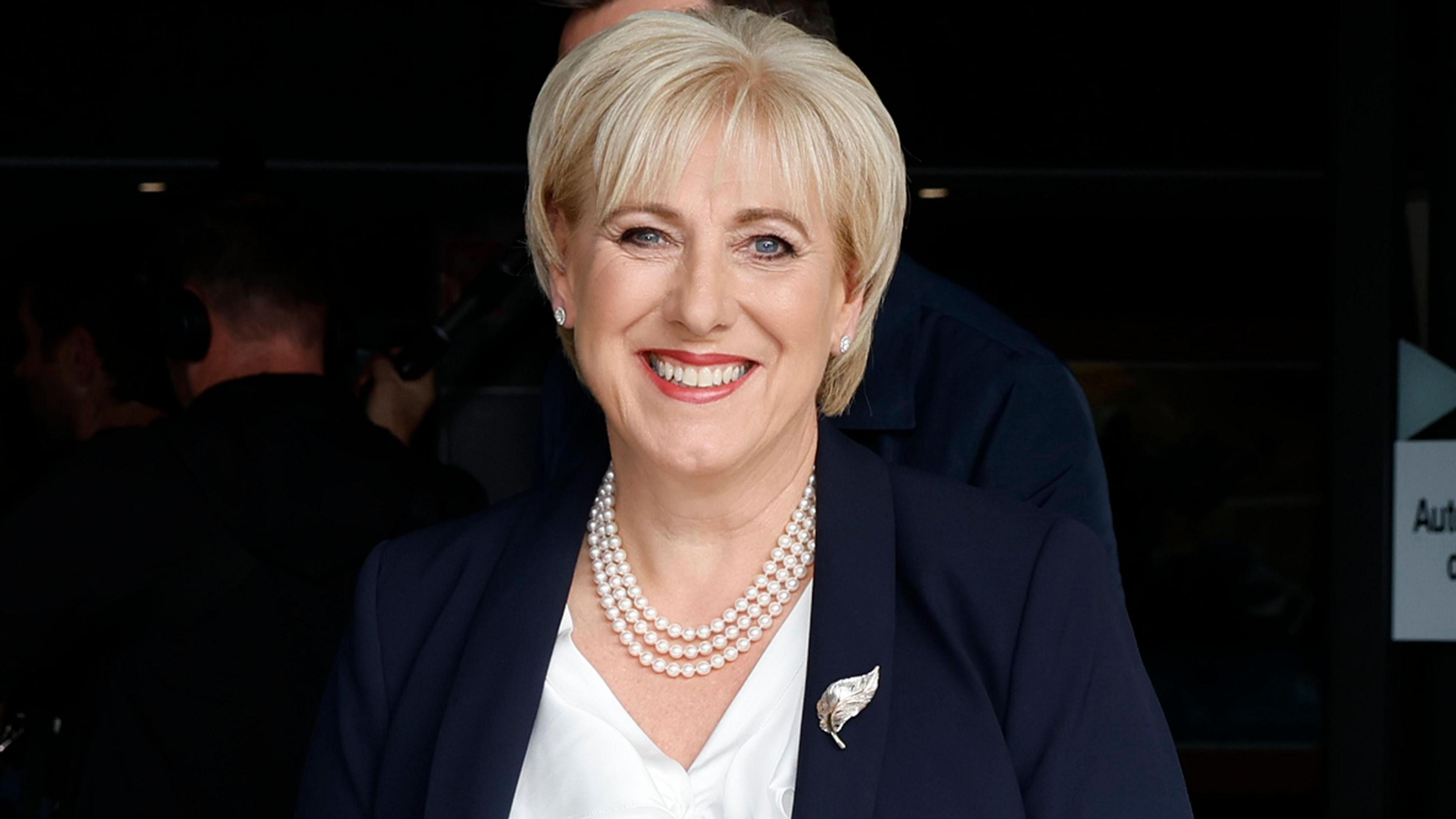 Irish presidential candidate, Fine Gael's Heather Humphreys, leaves the RTE studios. She is smiling at the camera. She has light hair and is wearing a navy blazer, white top and white necklace.